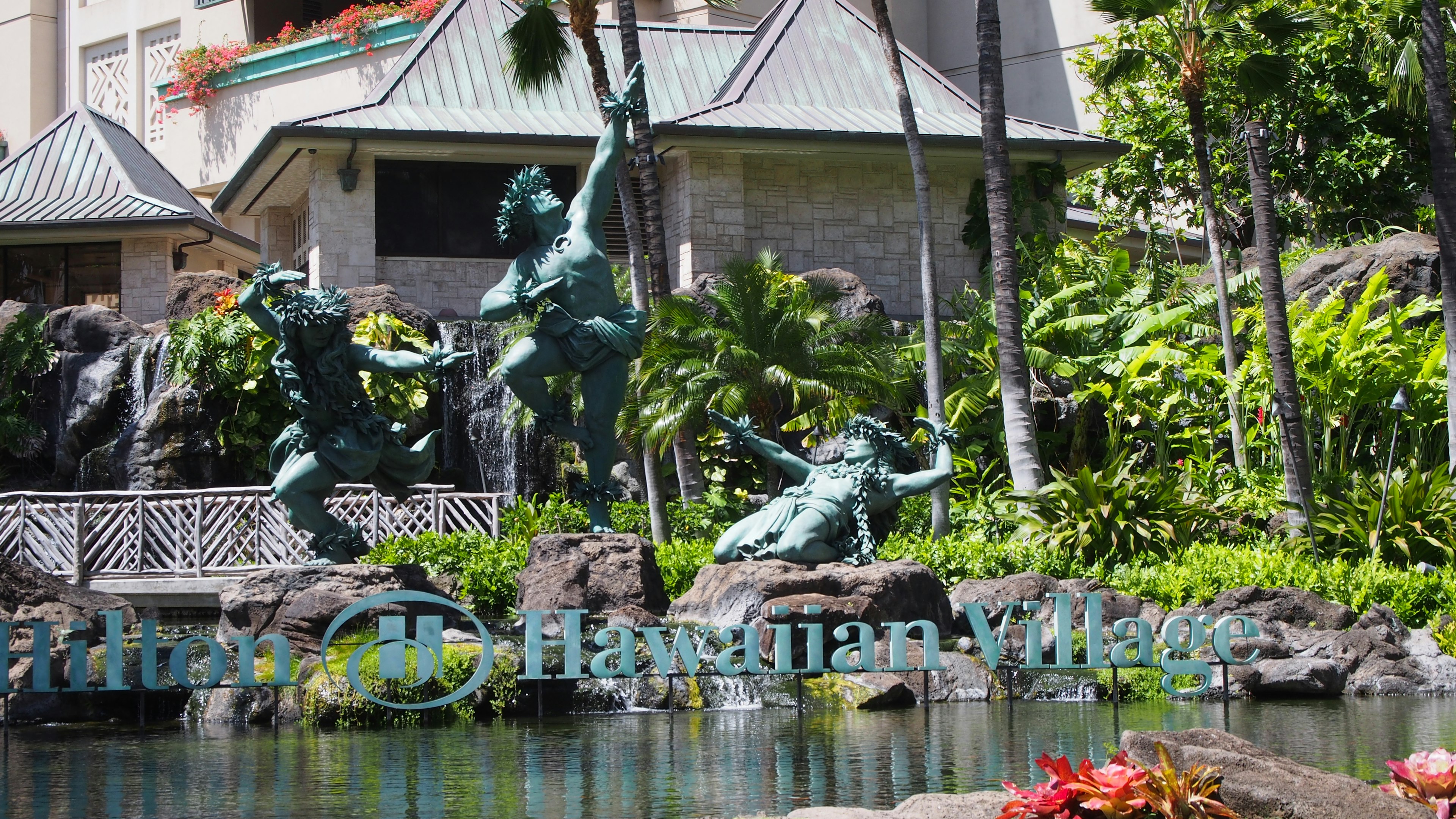 Hawaiian Village sculptures with lush greenery in the background