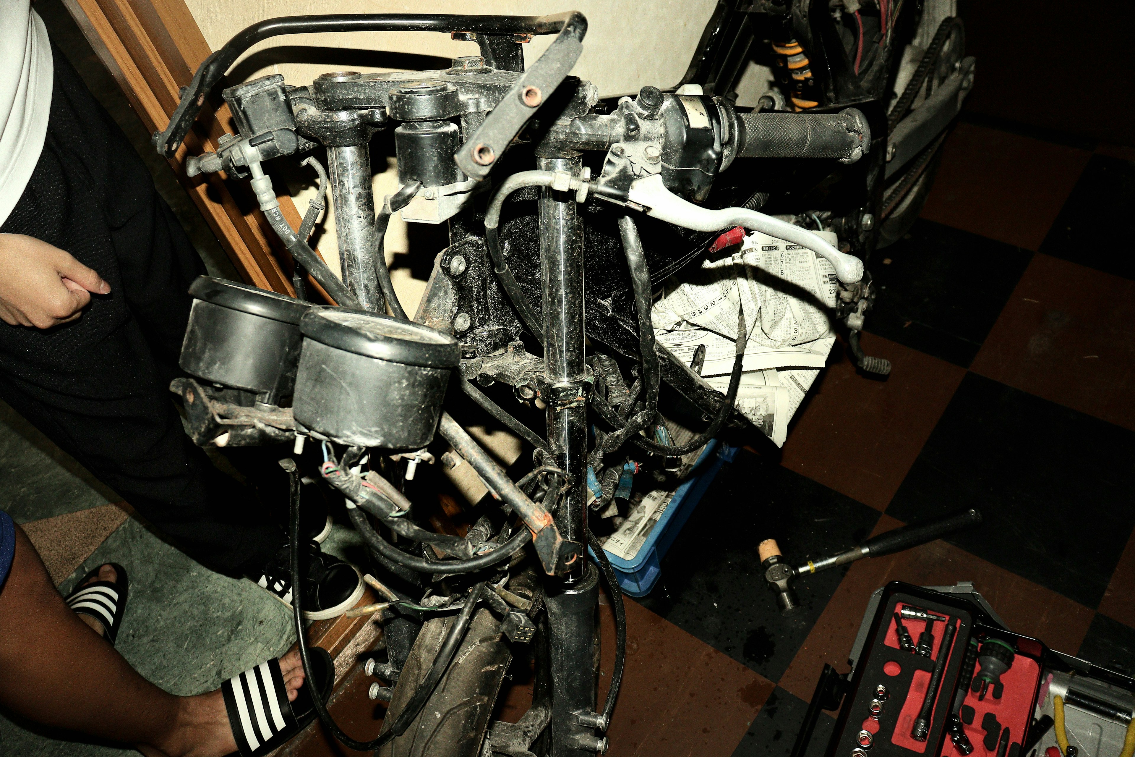 Photo of a motorcycle engine disassembled showing various parts and tools