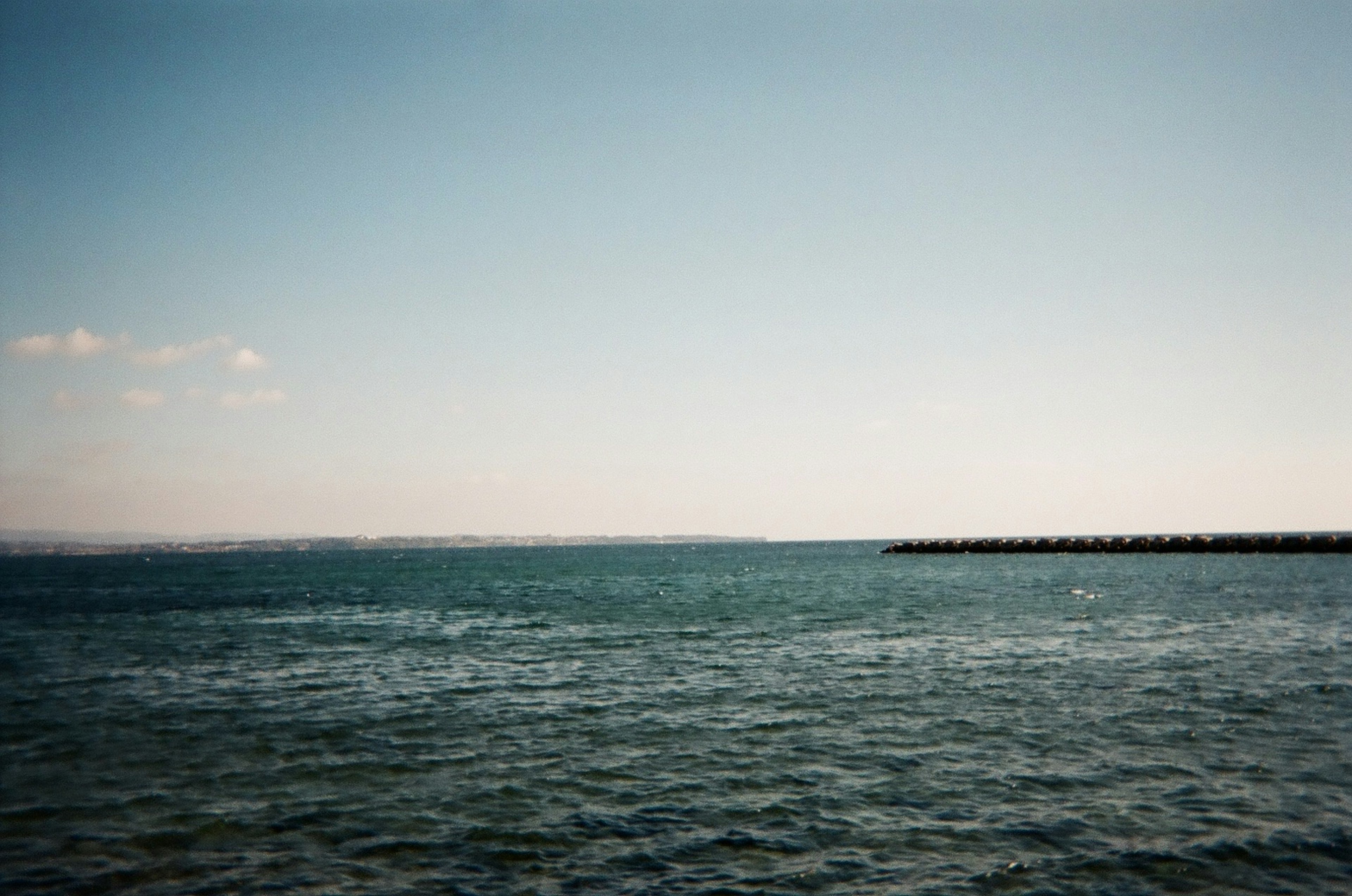 平靜的海洋和藍天場景 柔和的波浪和遠處的防波堤