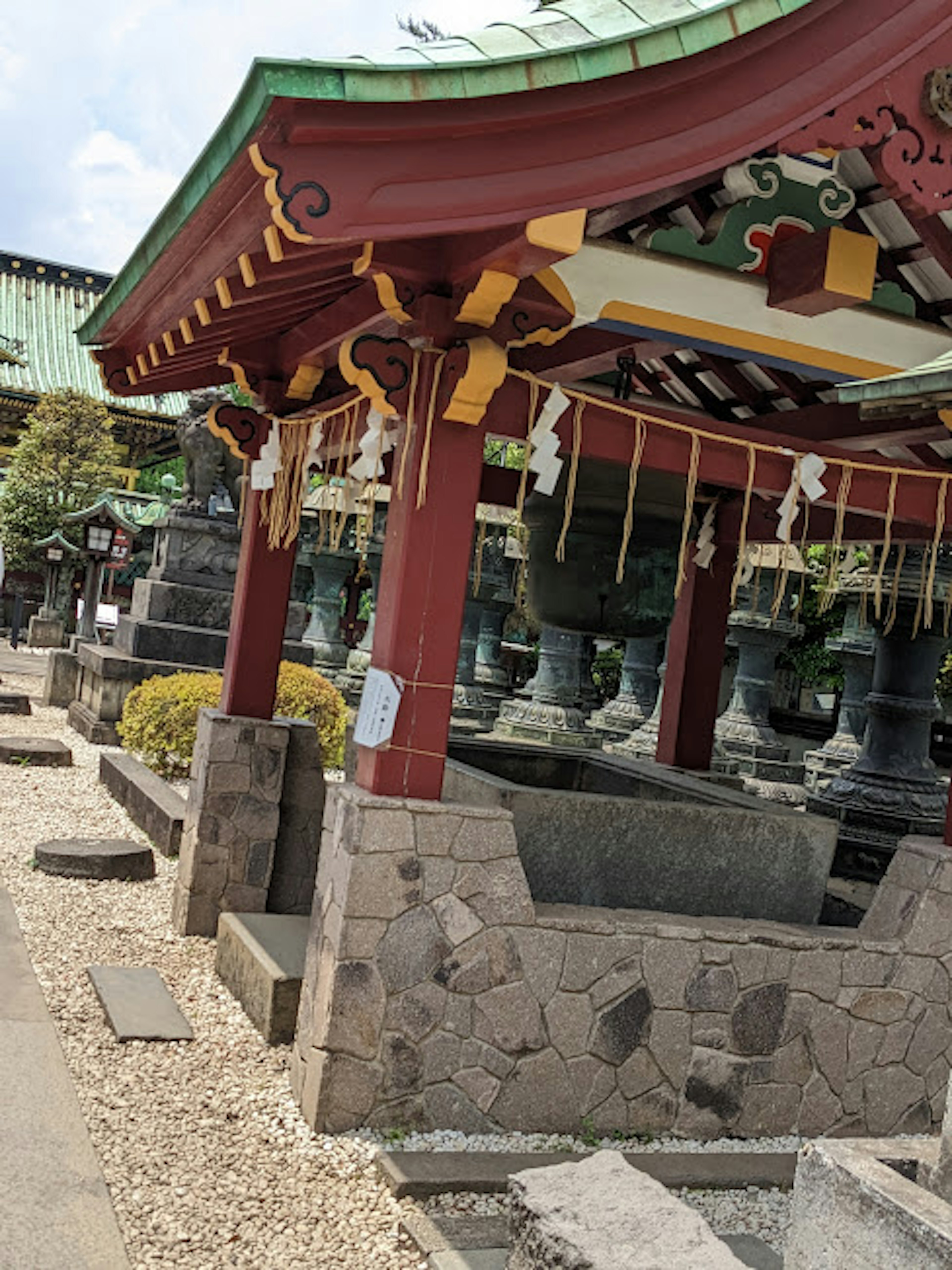 Red-roofed shrine structure surrounded by stone and garden