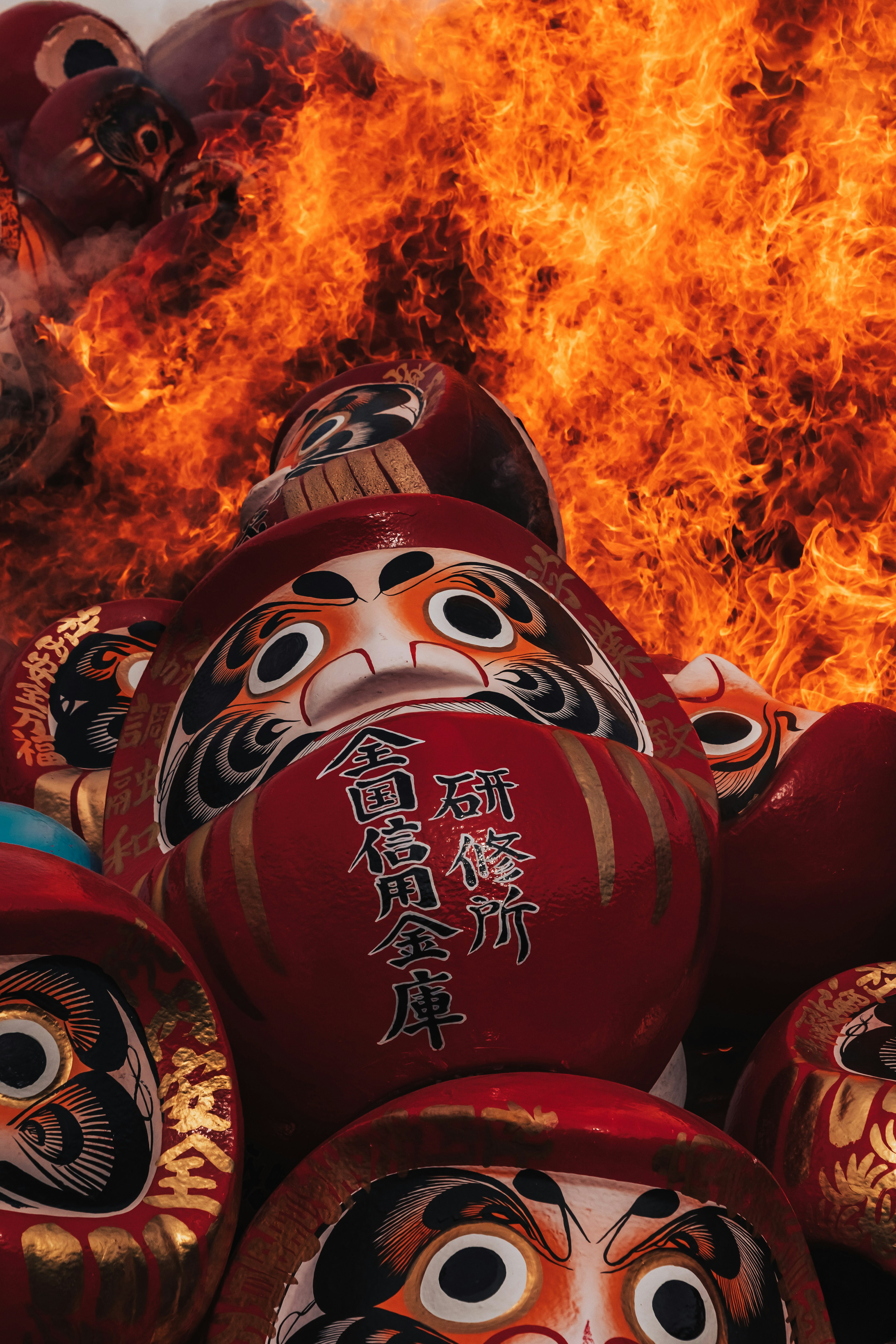 Muñecas daruma rojas rodeadas de llamas