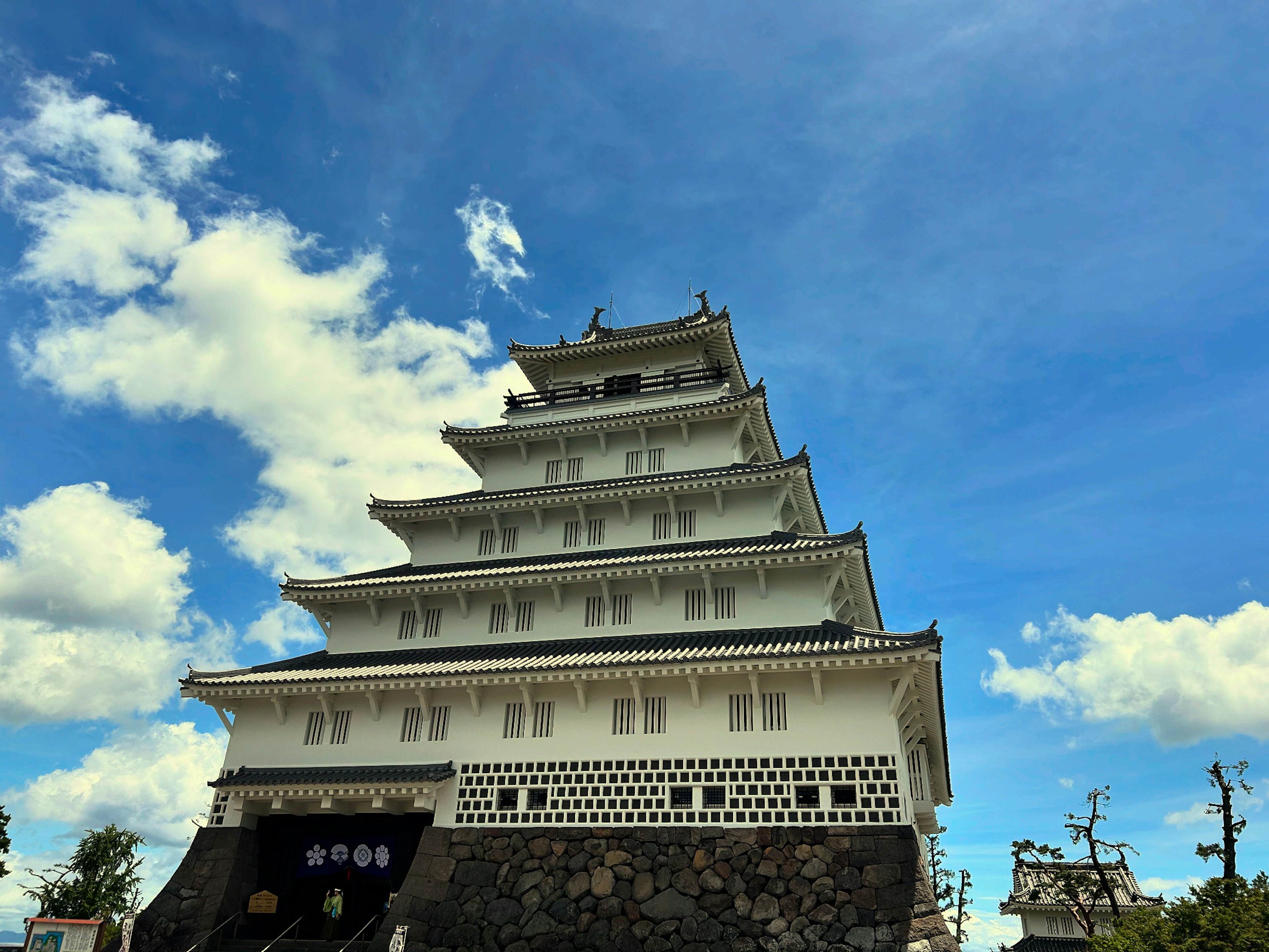 A white castle structure towering under a blue sky with intricate roof decorations