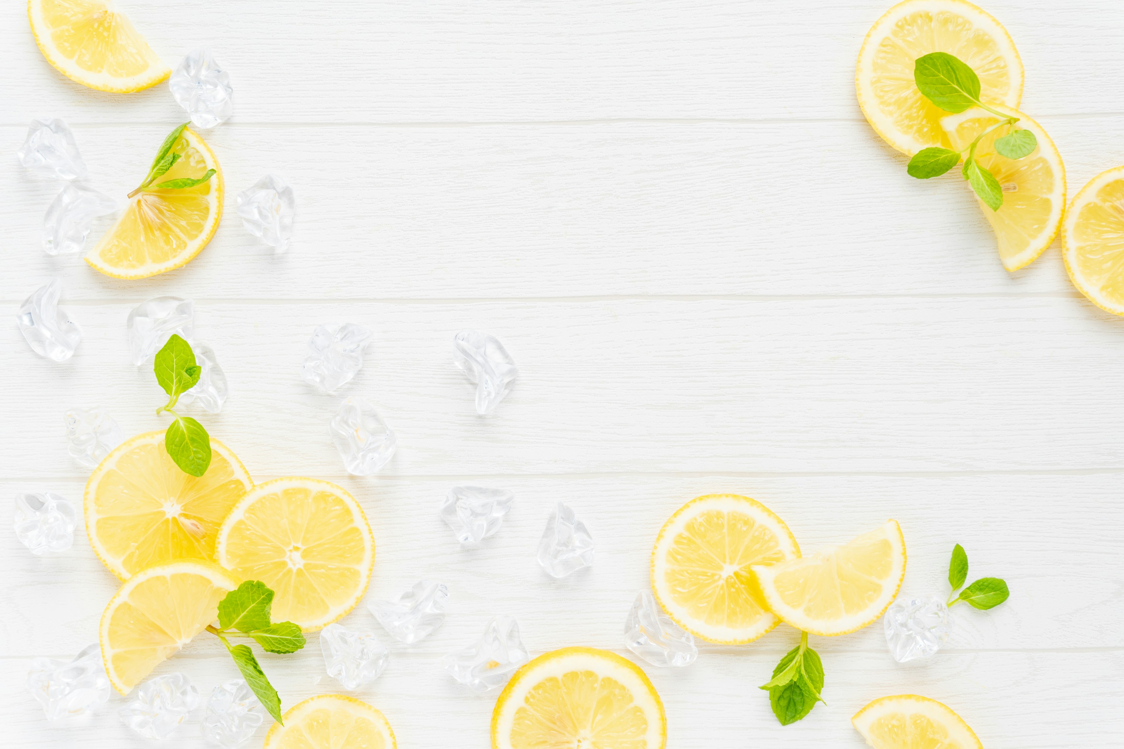 Sliced lemons and mint leaves arranged on ice with a bright background