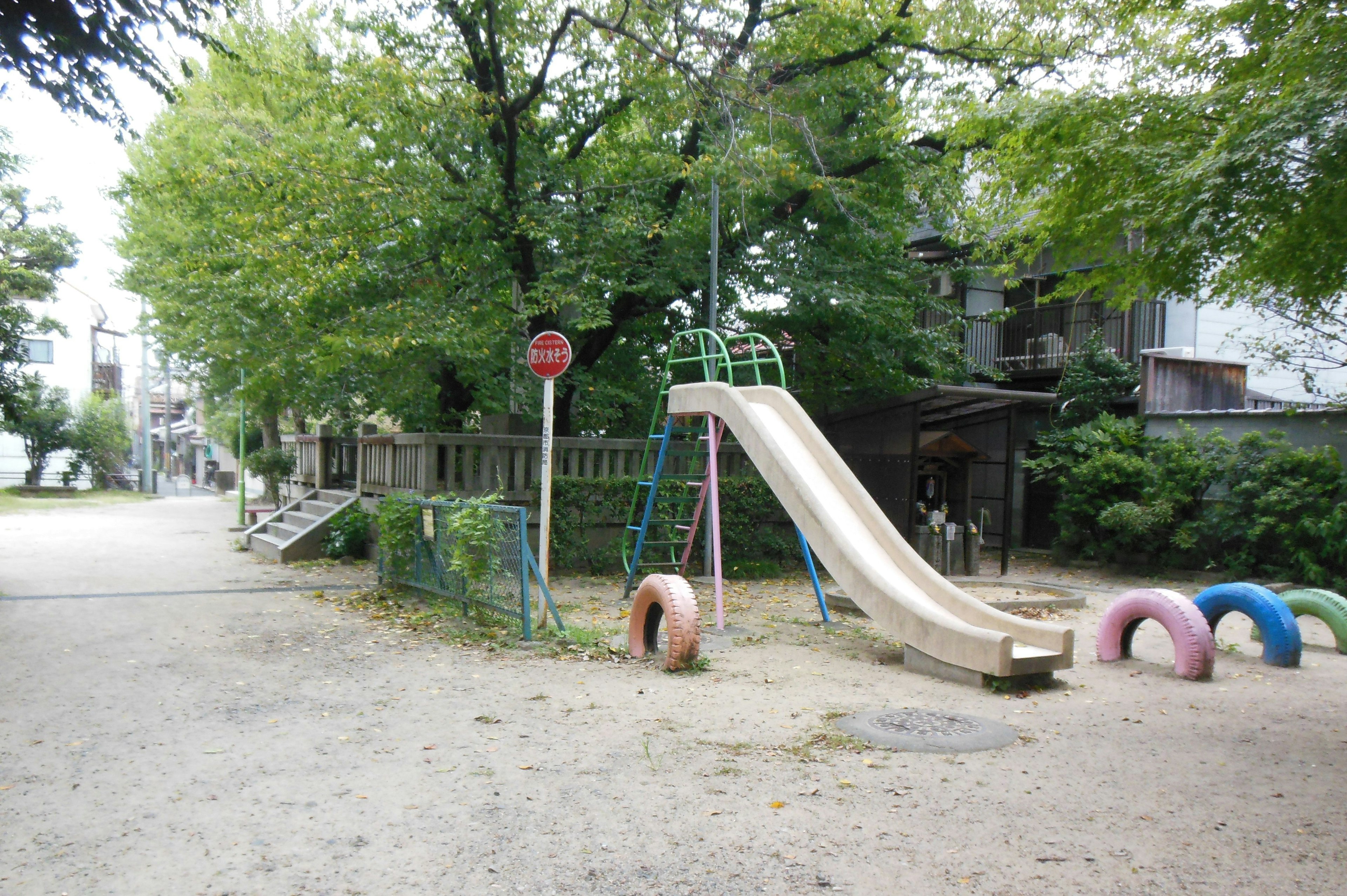 Escena de parque infantil con un tobogán y juguetes de neumáticos coloridos