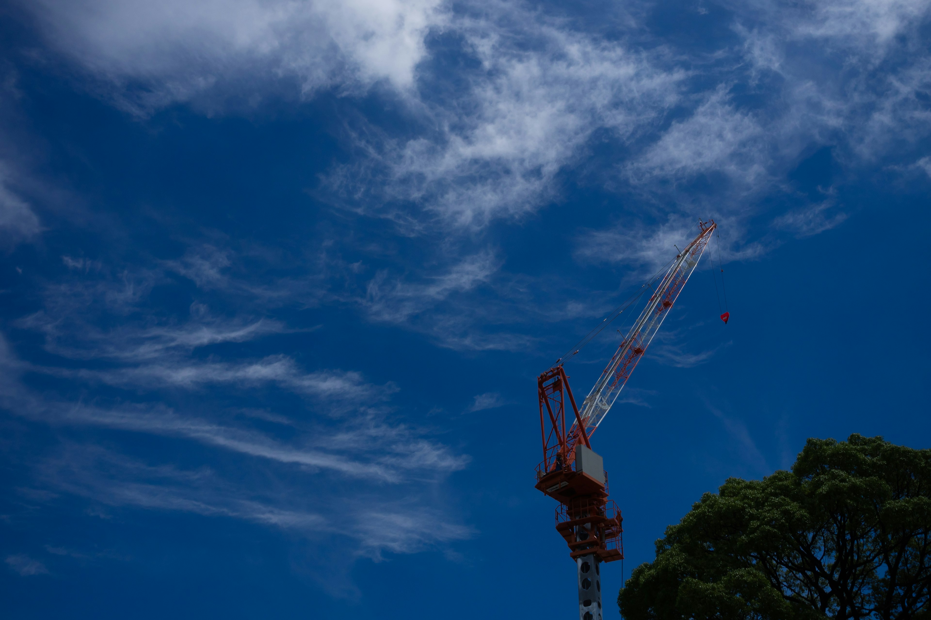 A red crane against a blue sky with white clouds