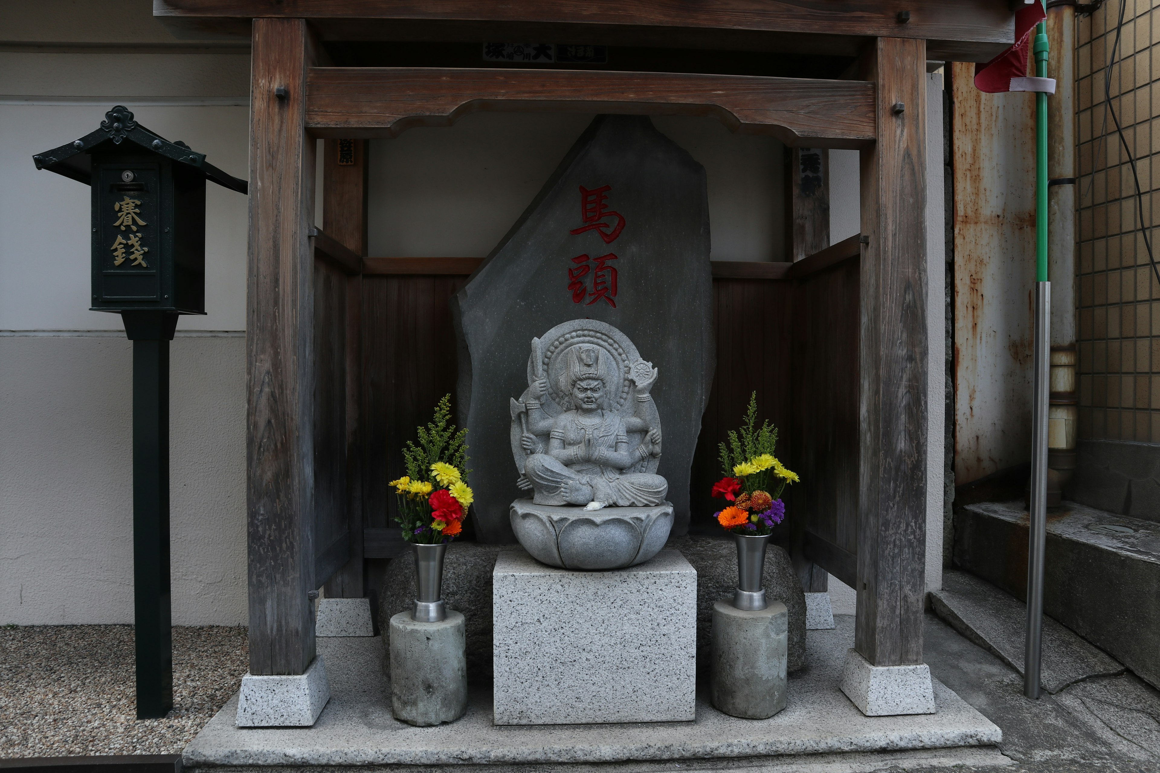 一個小神社，石像被五彩繽紛的花朵環繞