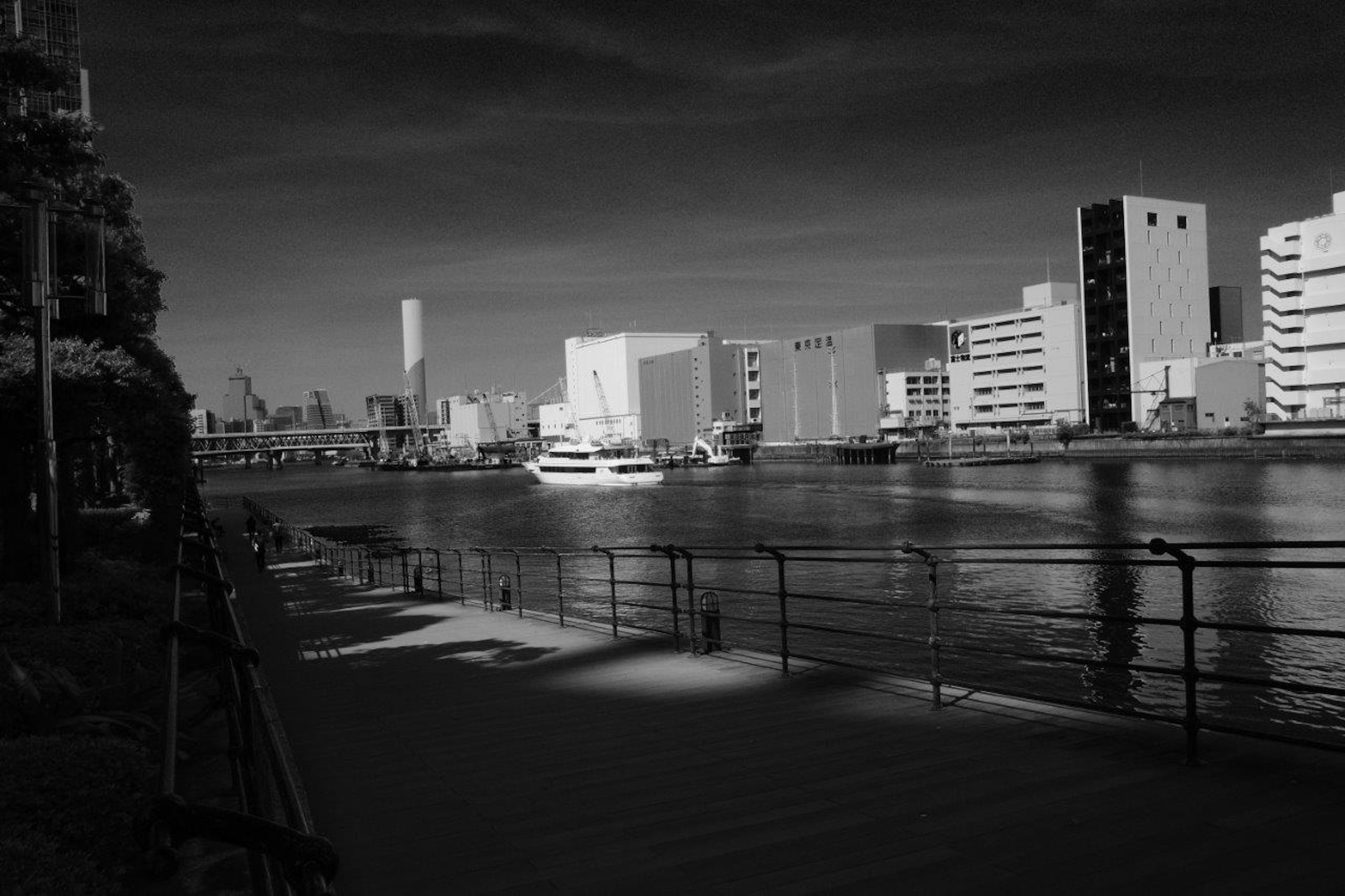 Black and white riverside scene featuring a boat and modern buildings