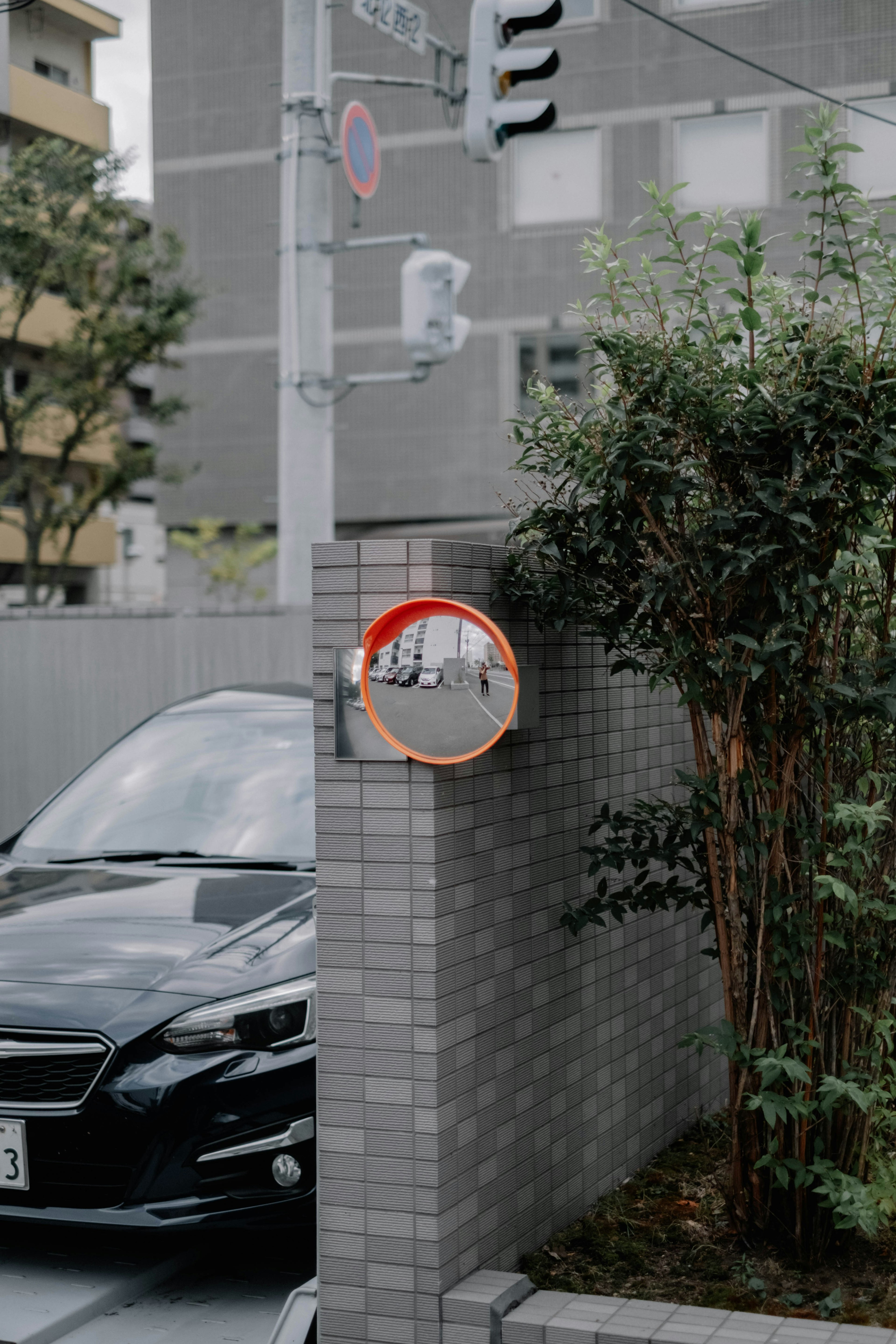 Scena urbana con un'auto nera e uno specchio riflettente