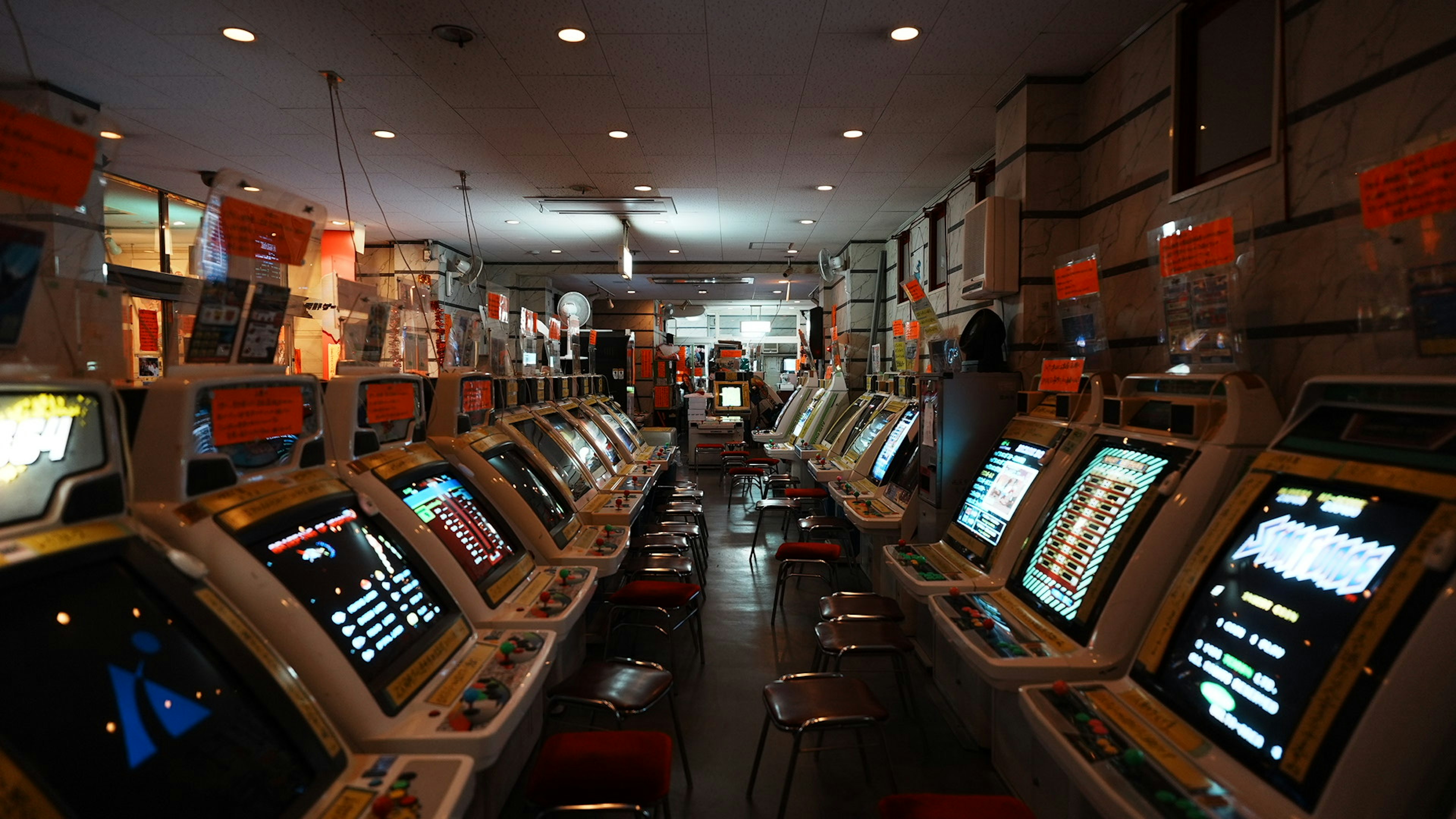 Intérieur d'une arcade avec de nombreuses machines de jeu et un éclairage lumineux