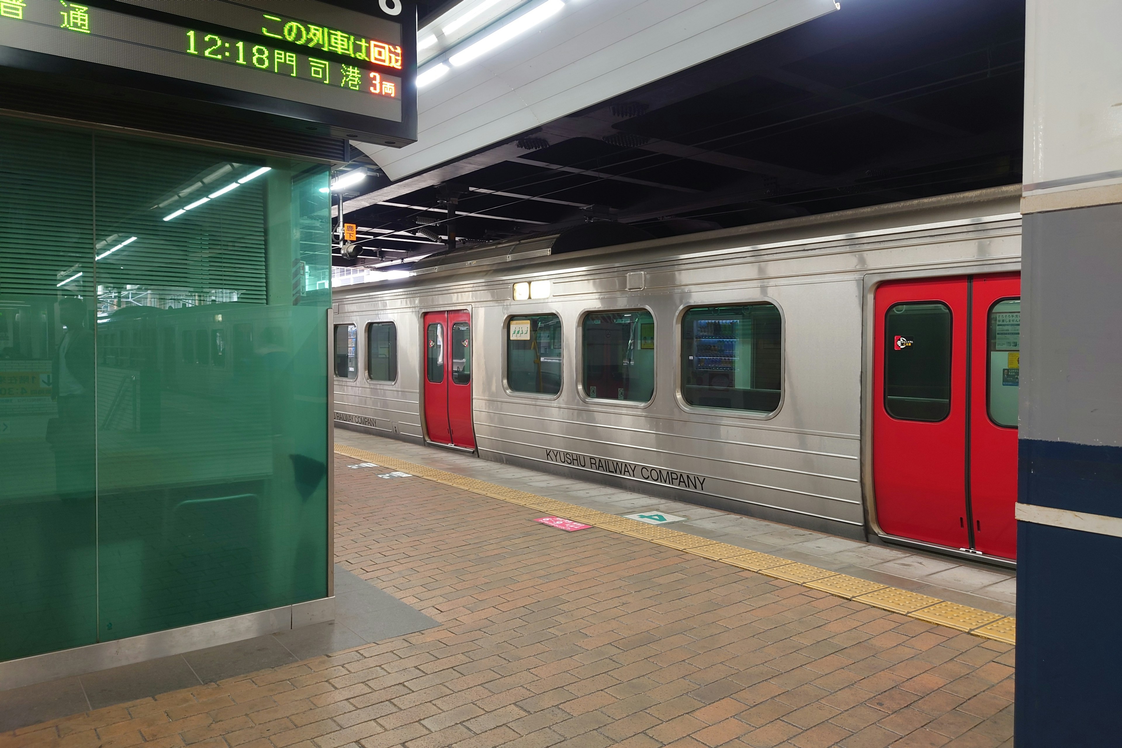 Platform with a silver train featuring red doors at a subway station