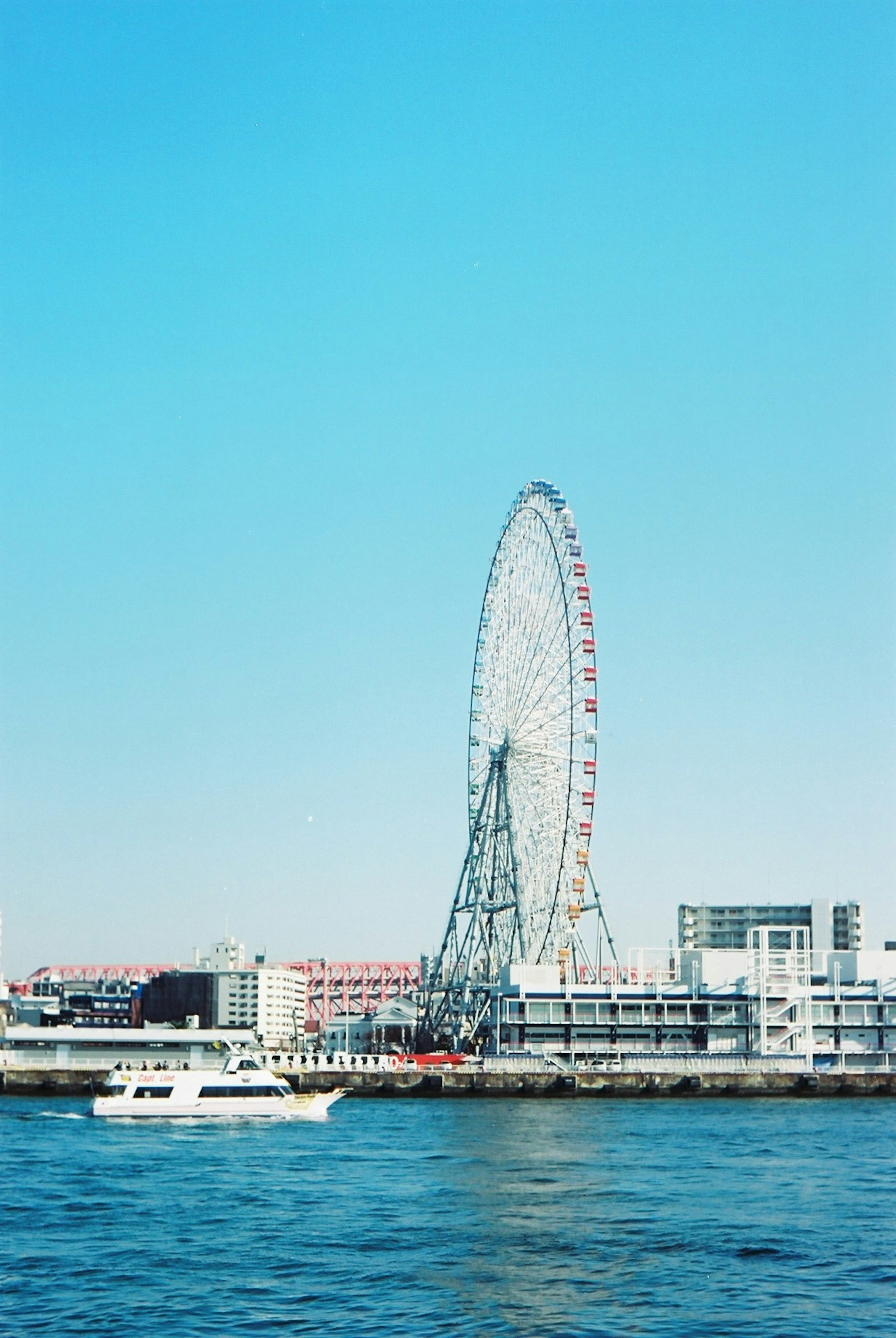 青い空の下にある観覧車と海に浮かぶボート