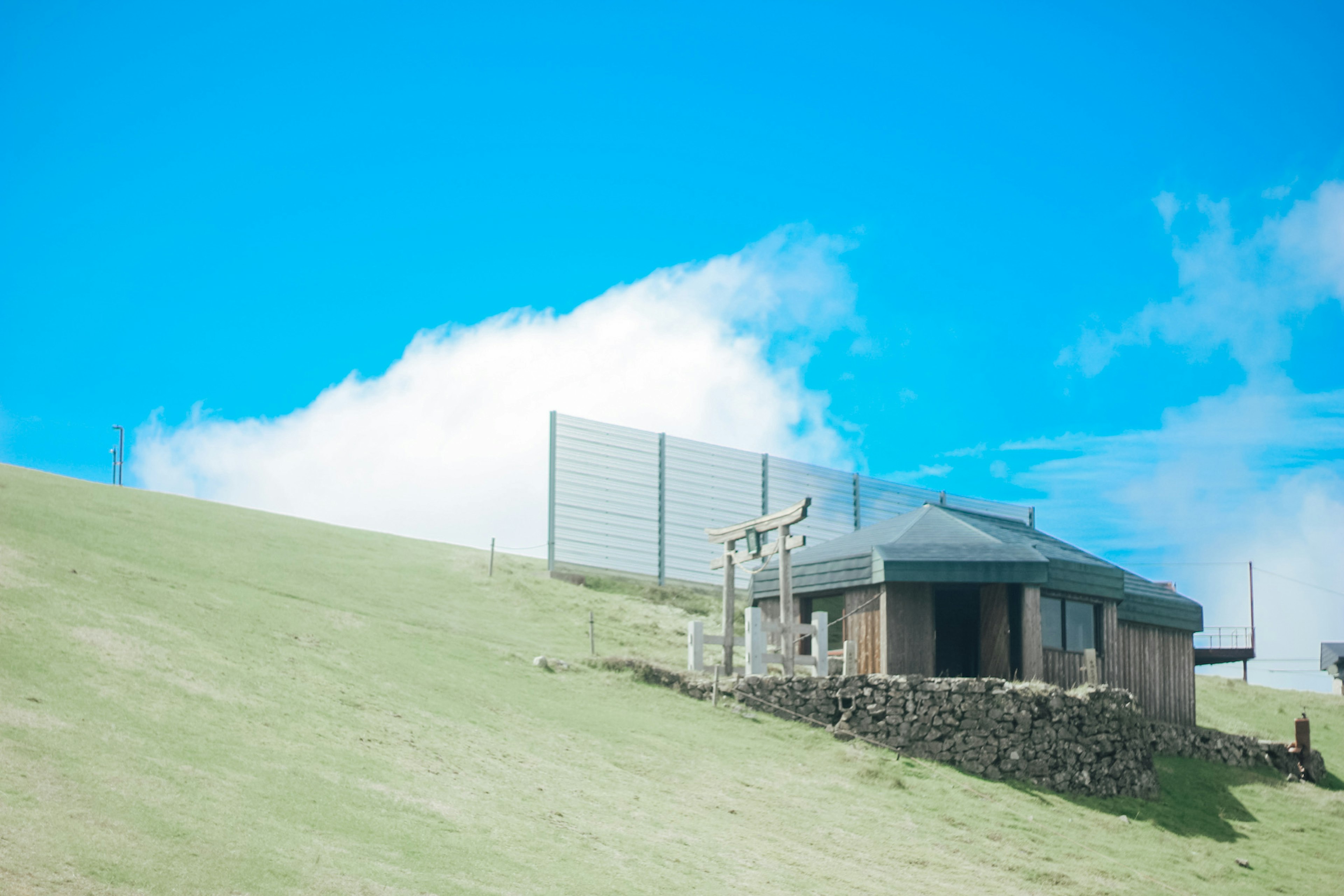 Una pequeña casa de madera en una colina cubierta de hierba bajo un cielo azul claro