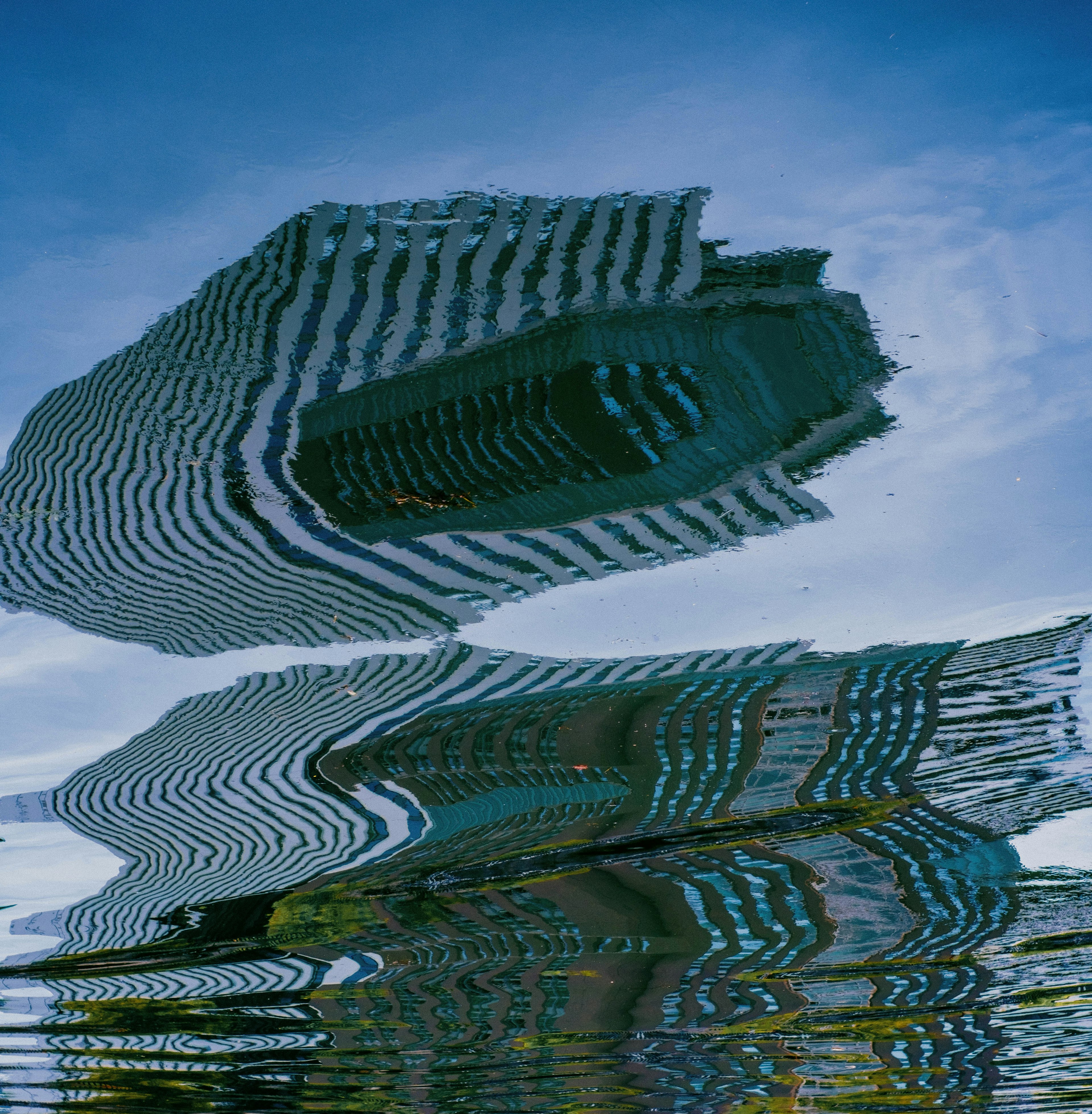 Verzerrte Reflexion von Gebäuden im Wasser mit blauem Himmel