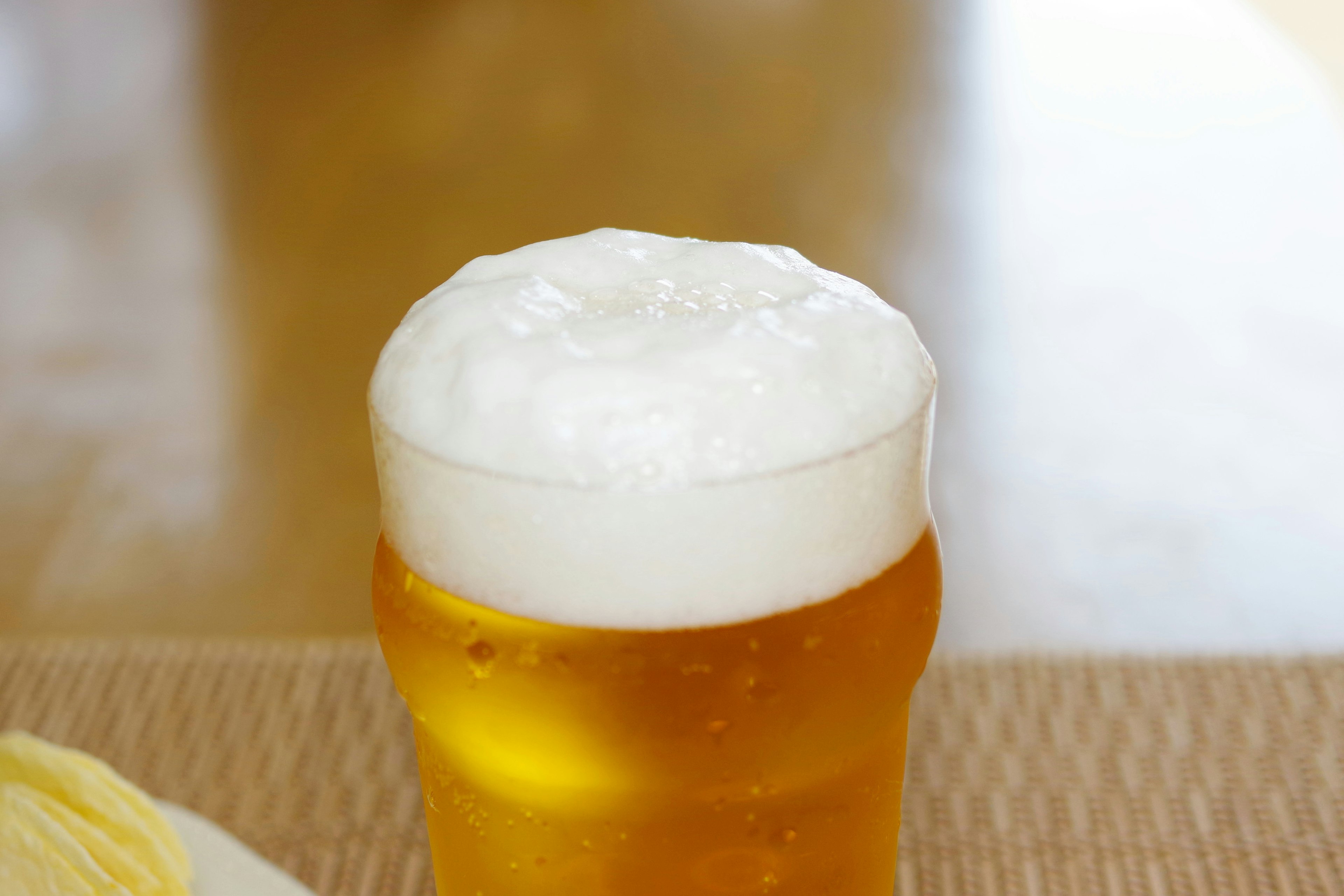 Frothy beer in a glass with a wooden table background