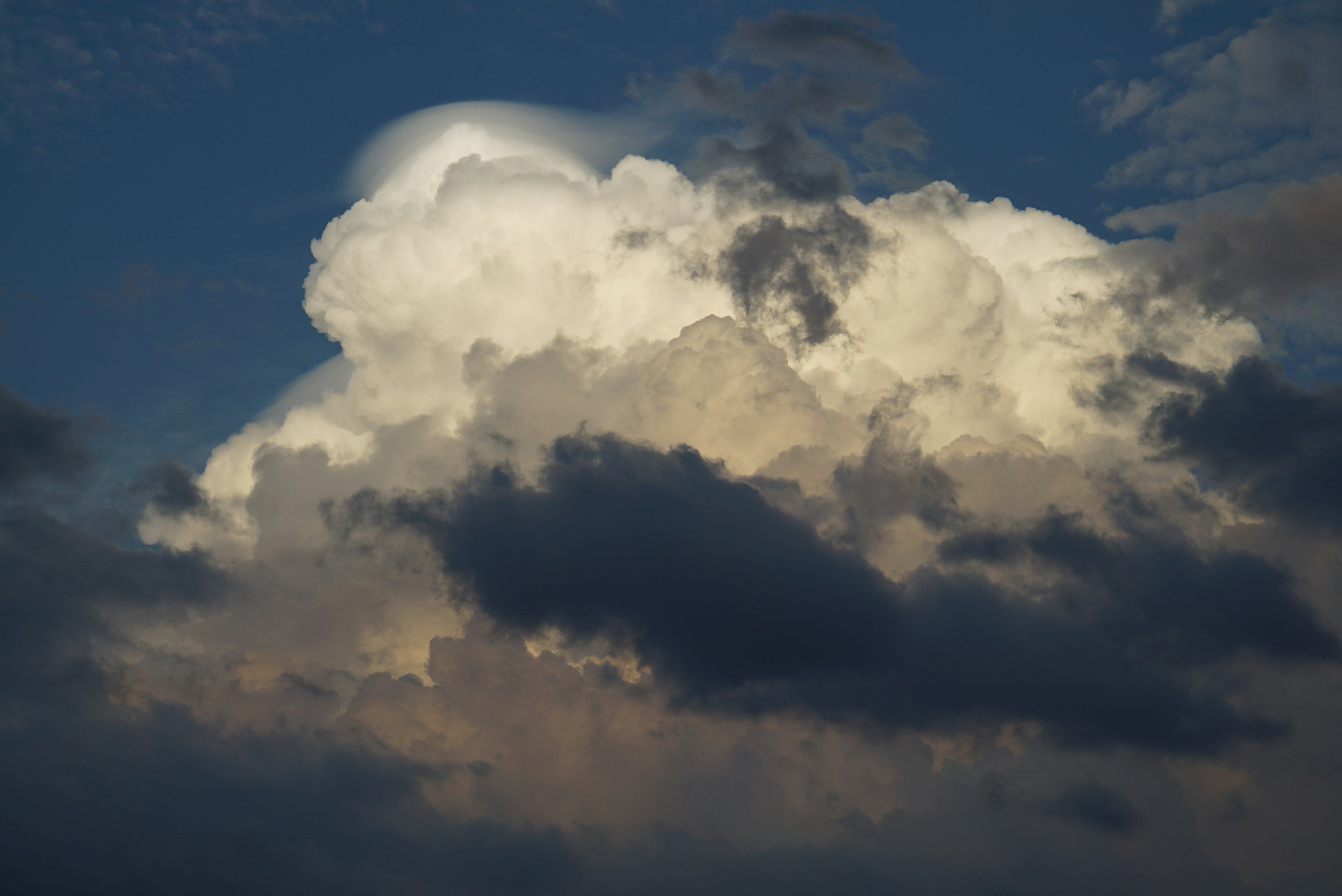 Kontrast von weißen Wolken und dunklen Wolken vor blauem Himmel