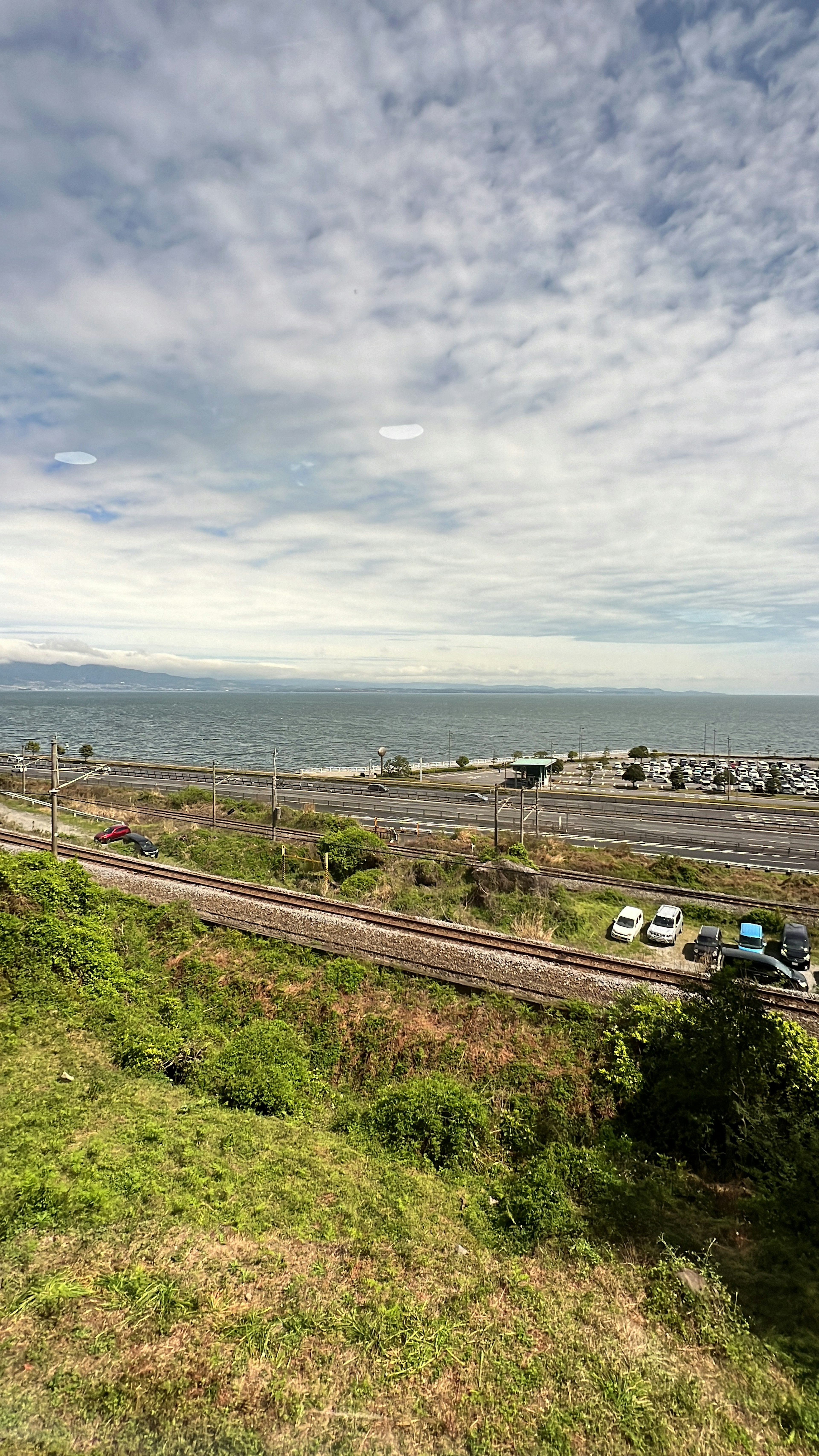 Pemandangan pantai dengan langit biru rumput hijau dan rel kereta yang terlihat