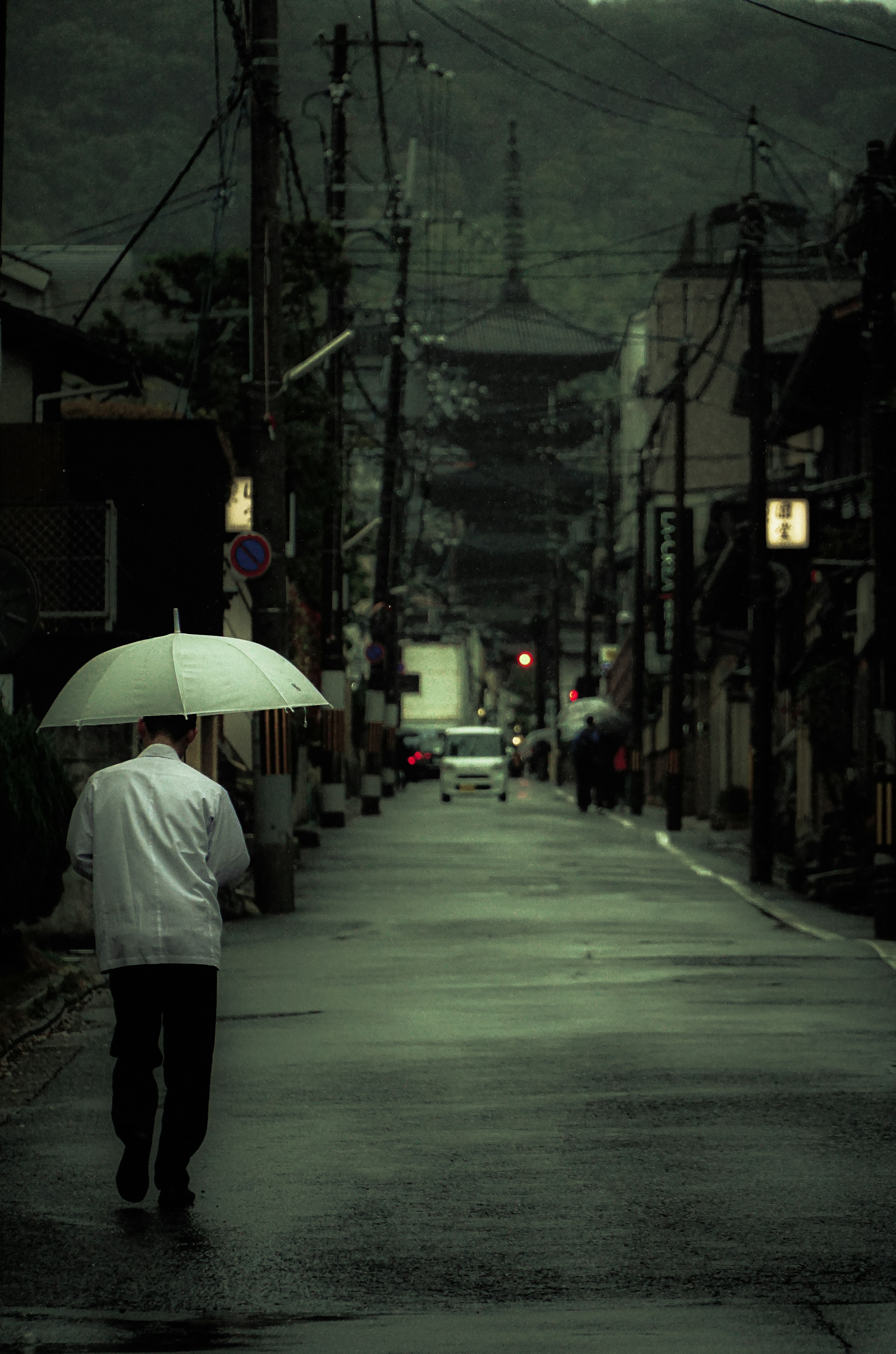 A person walking with an umbrella in a quiet street on a rainy day