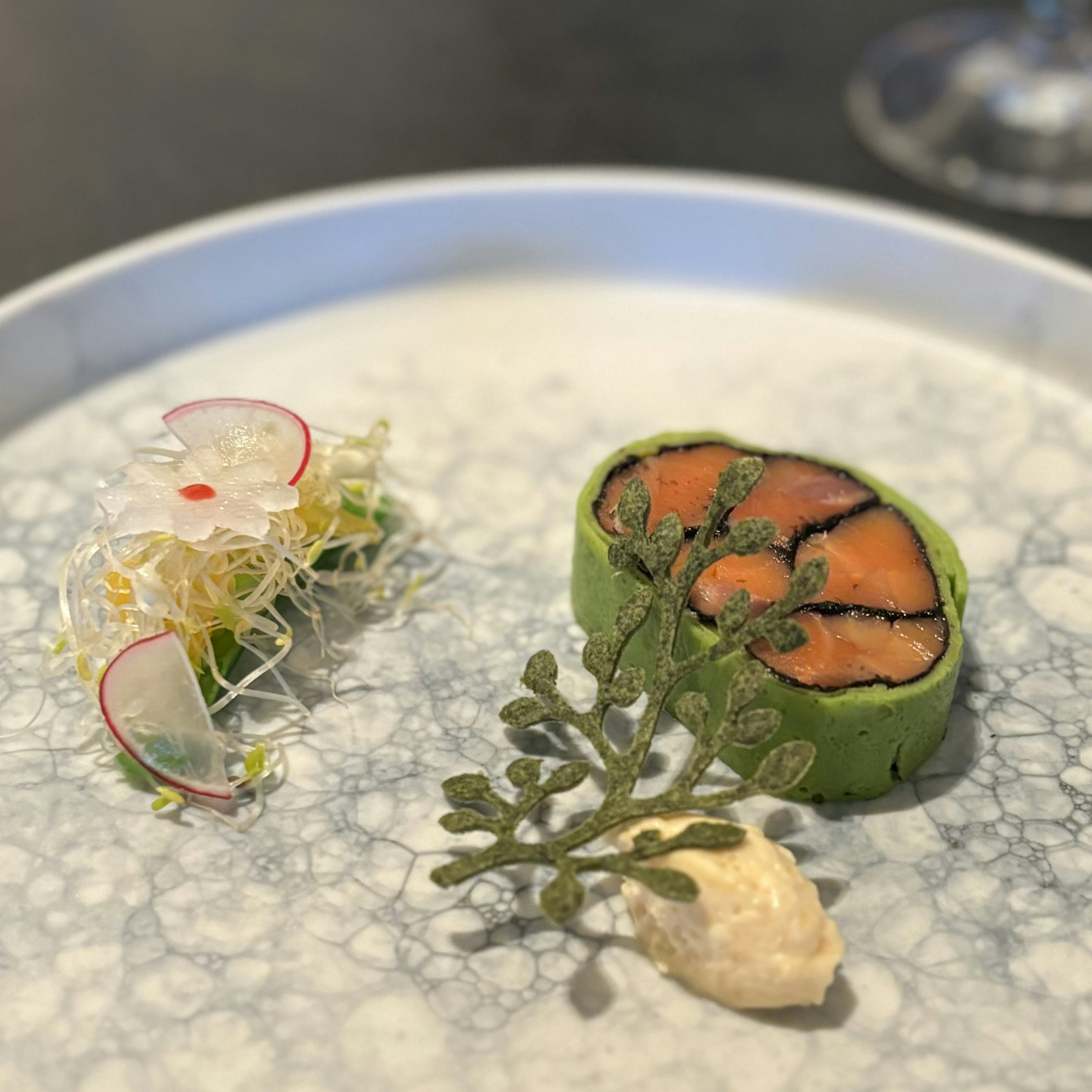 Piatto di sushi elegantemente impiattato con rotolo di alga verde e fiore di ravanello