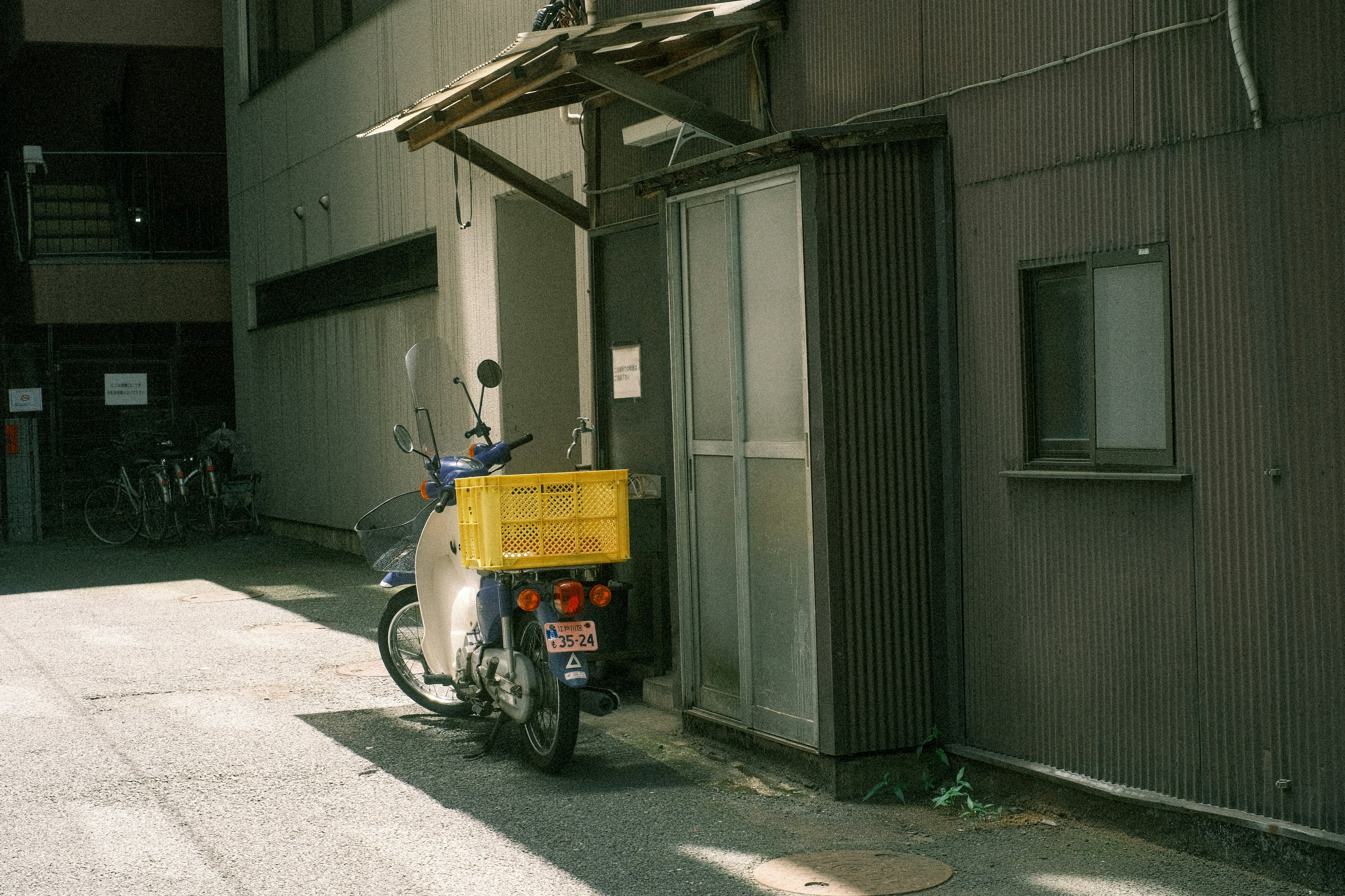 Delivery motorcycle with a yellow box parked in a narrow alley beside an old building