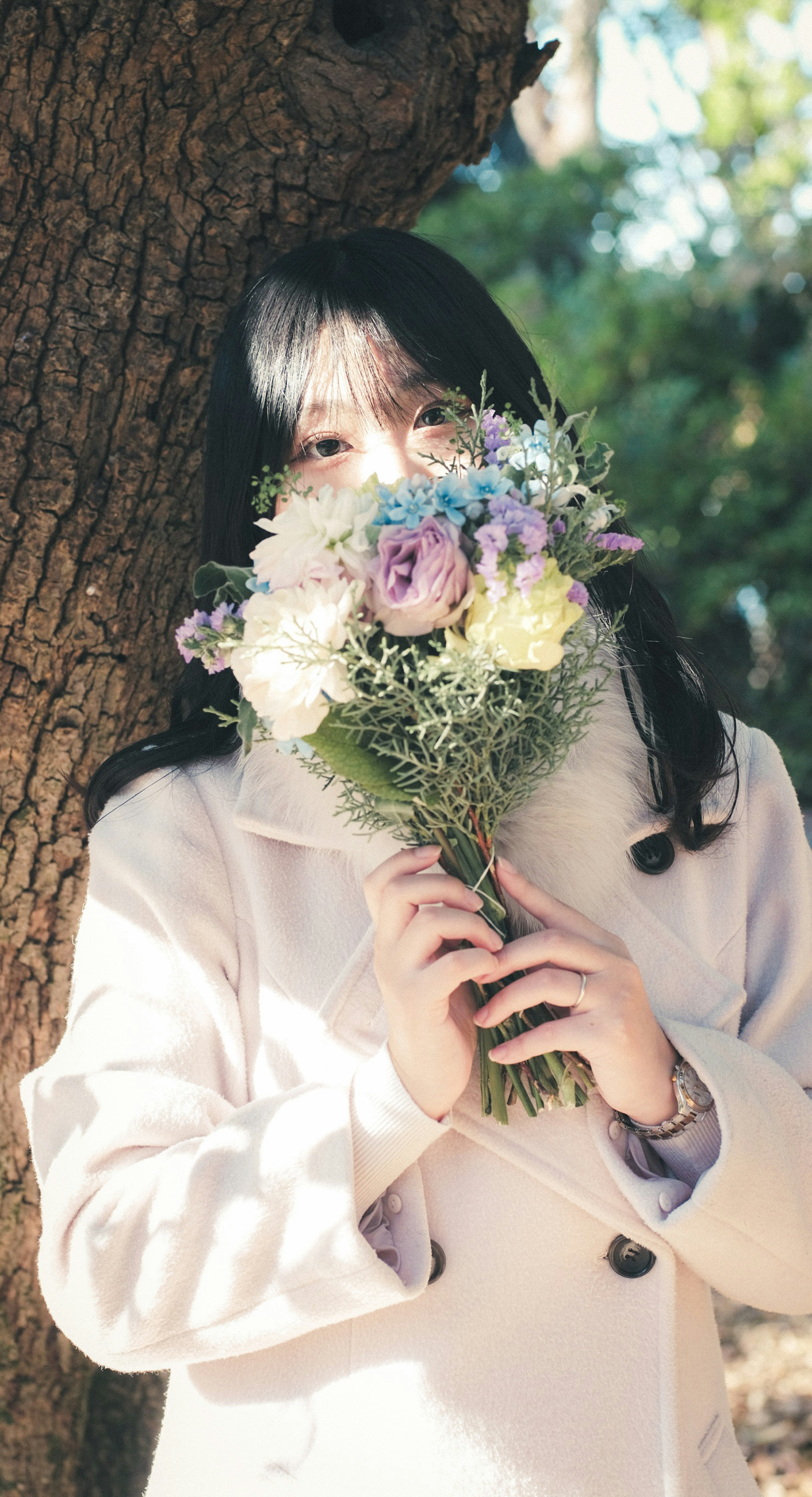 Une femme tenant un bouquet de fleurs près d'un arbre