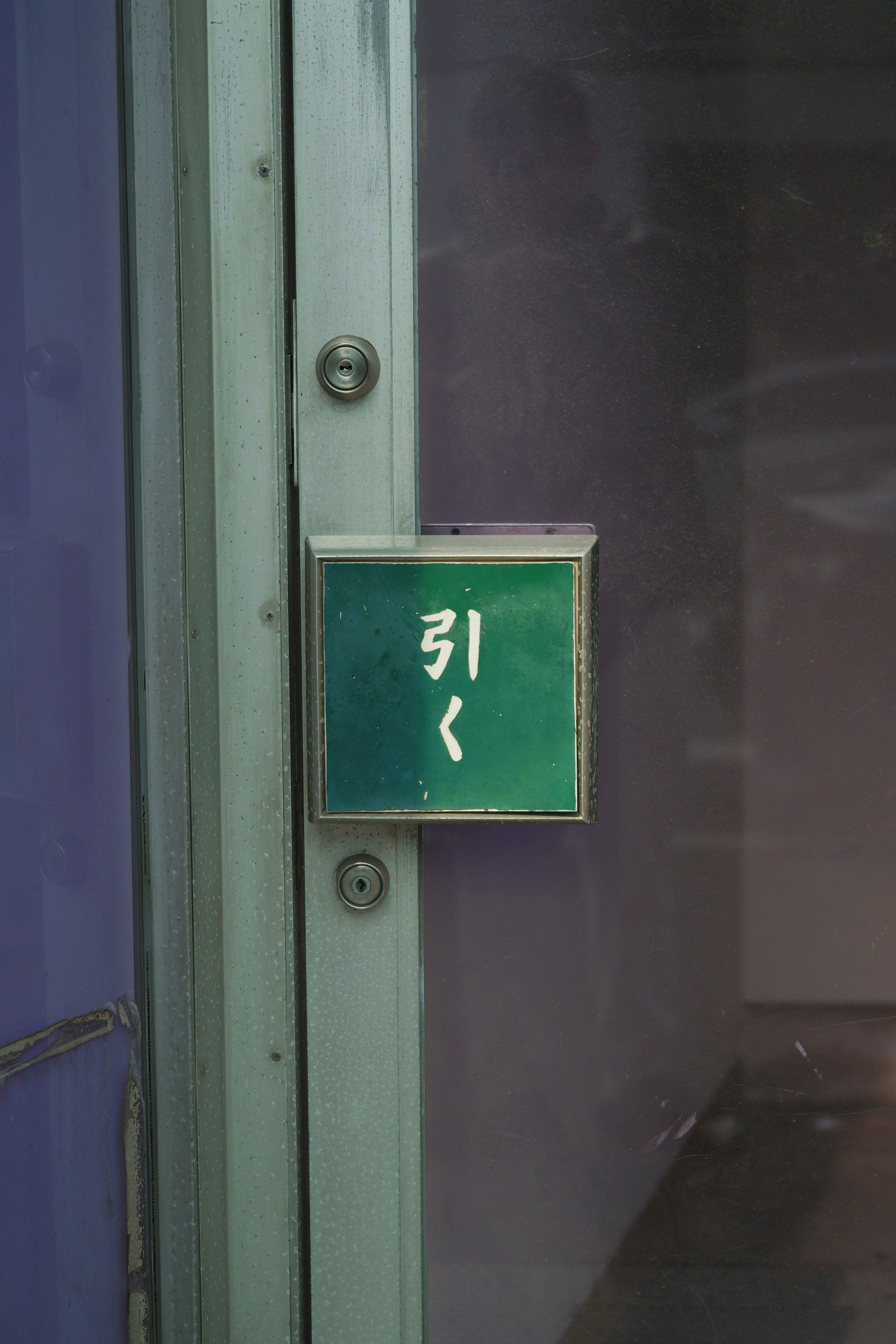 Green sign with the word '引く' attached to a door