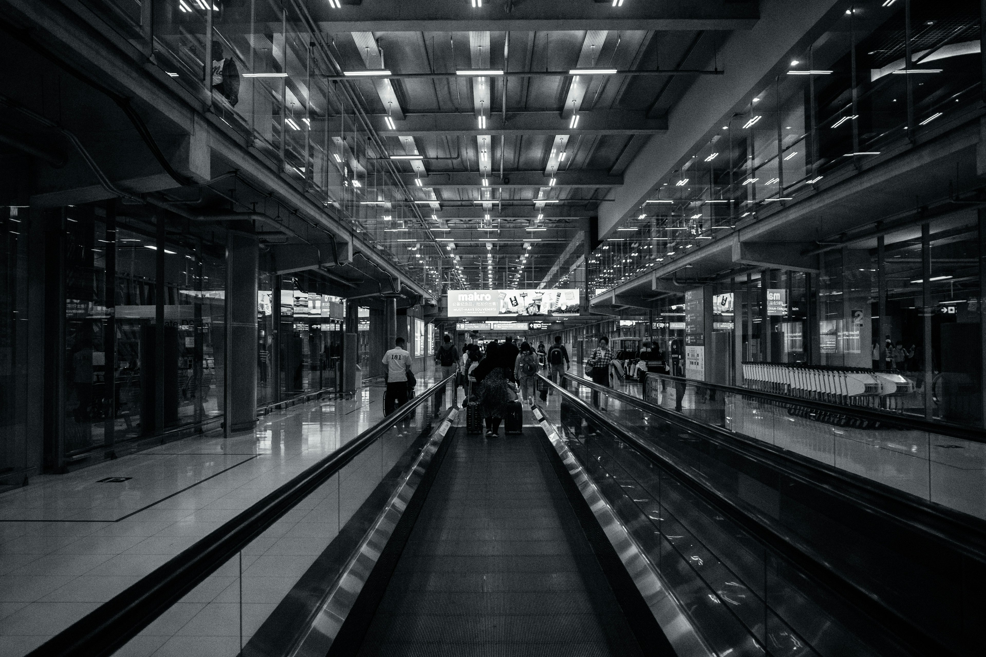 Koridor bandara modern dengan pencahayaan cerah dan orang-orang yang bergerak