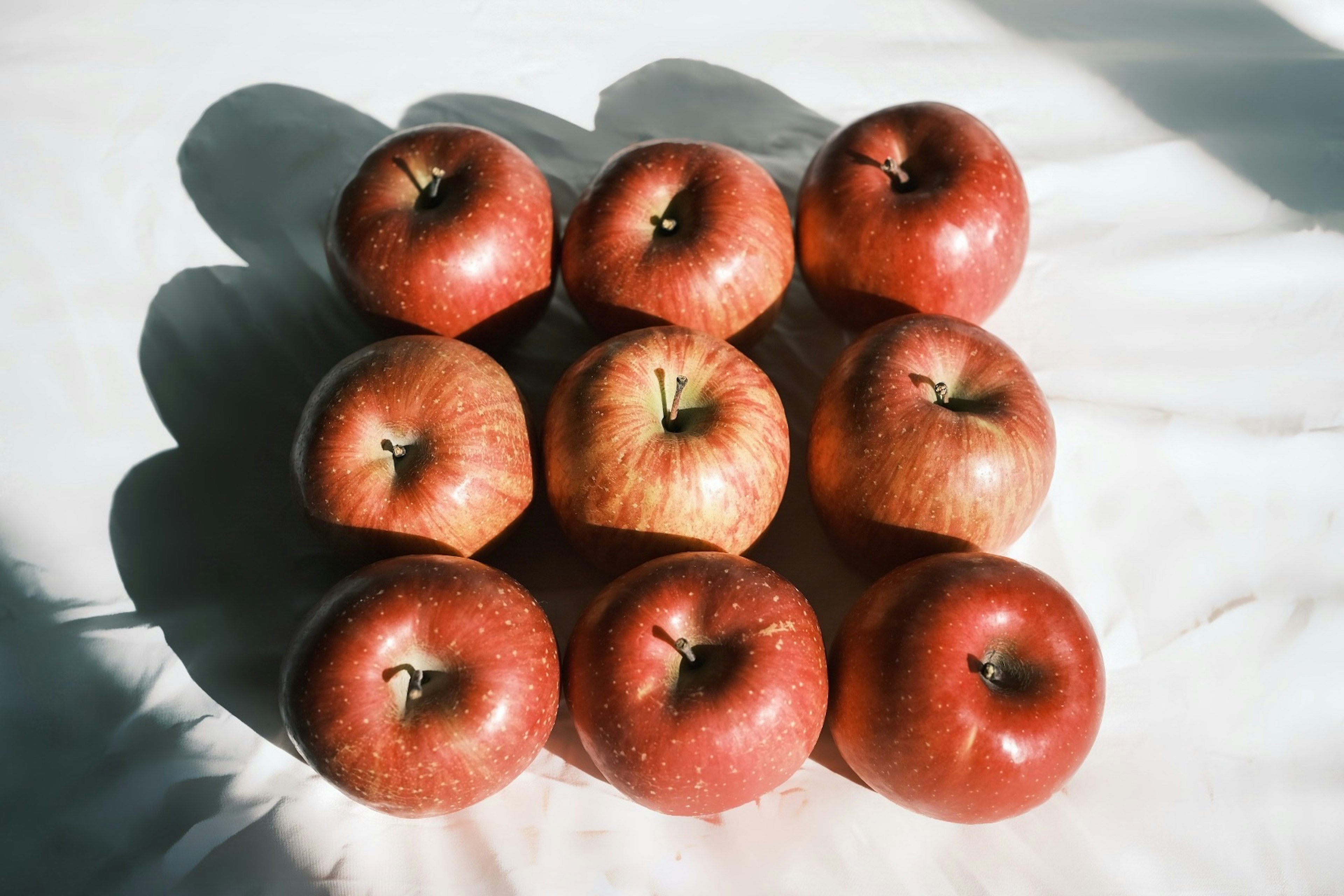 A neat arrangement of red apples on a light surface