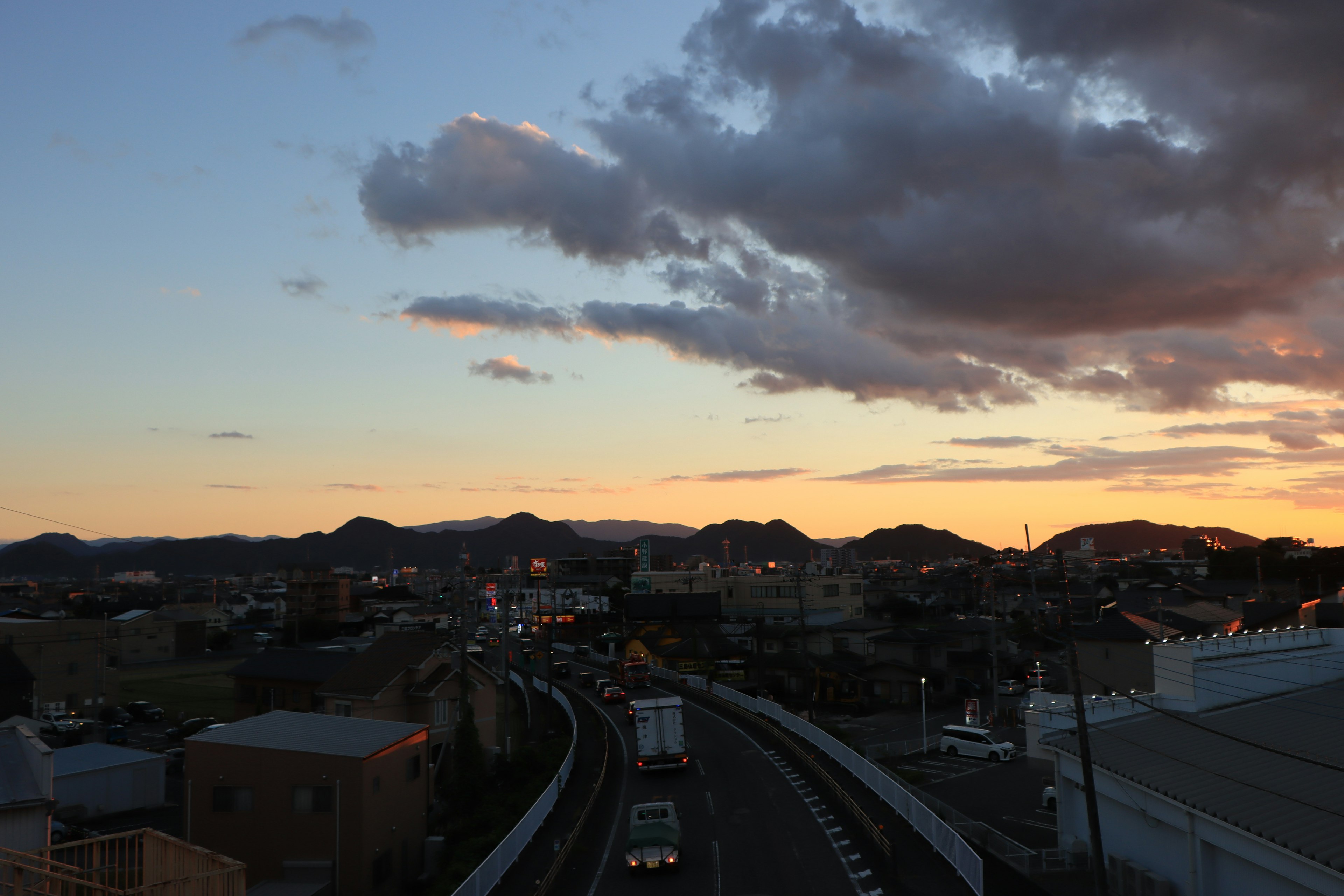 夕焼けの空と山々を背景にした都市の風景