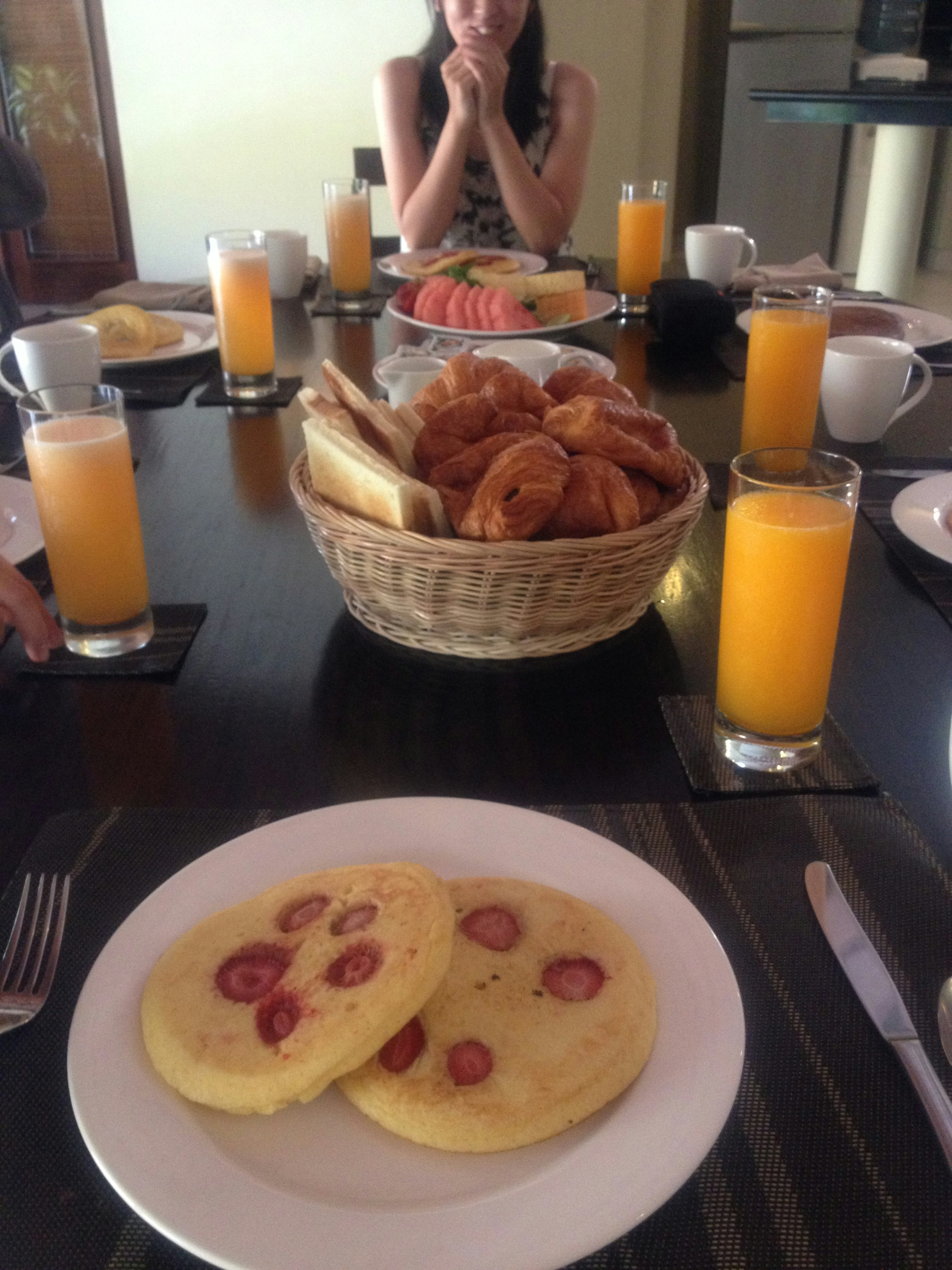 Breakfast table featuring pancakes with strawberries and croissants