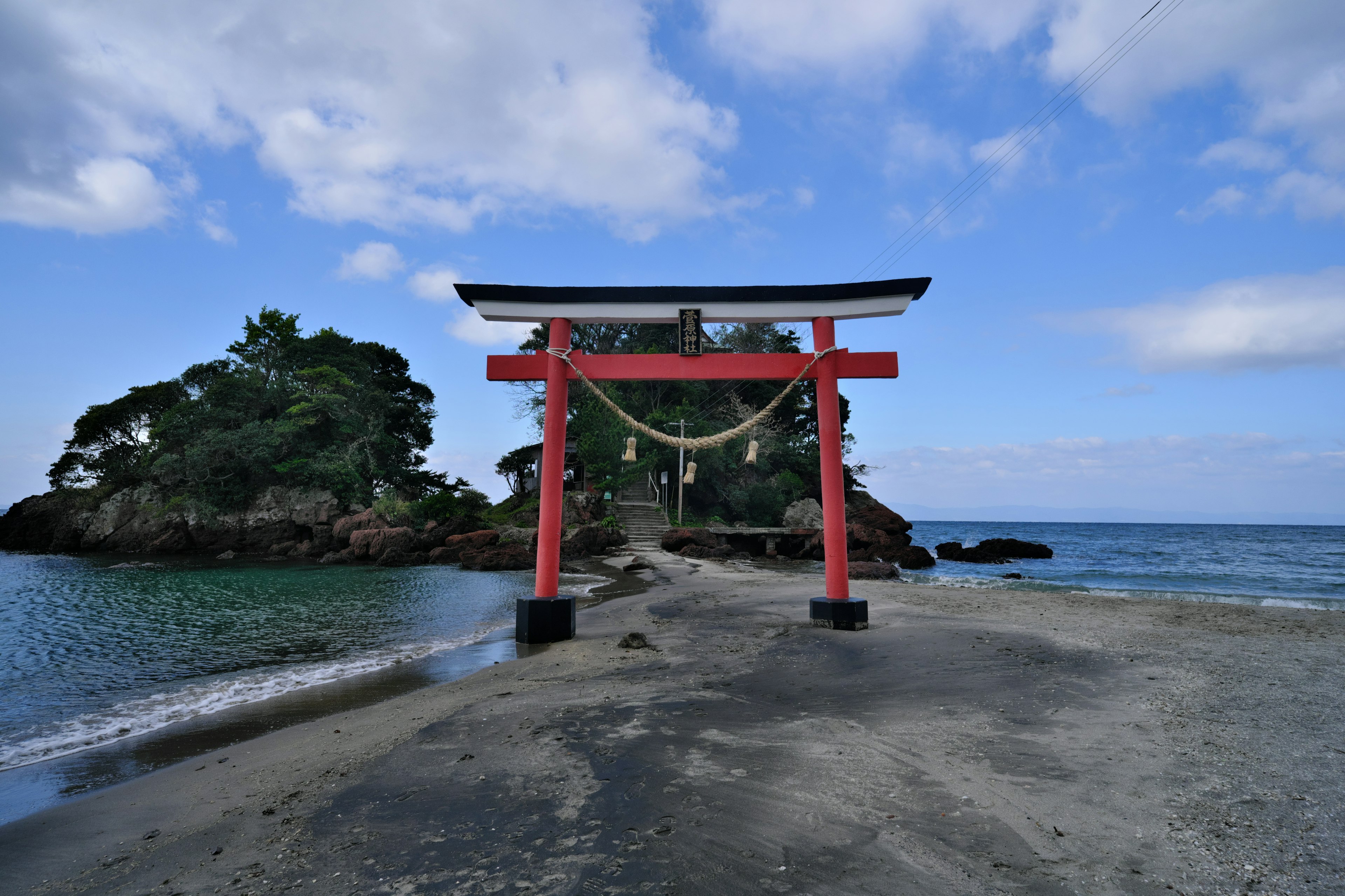 赤い鳥居が海辺に立っている風景