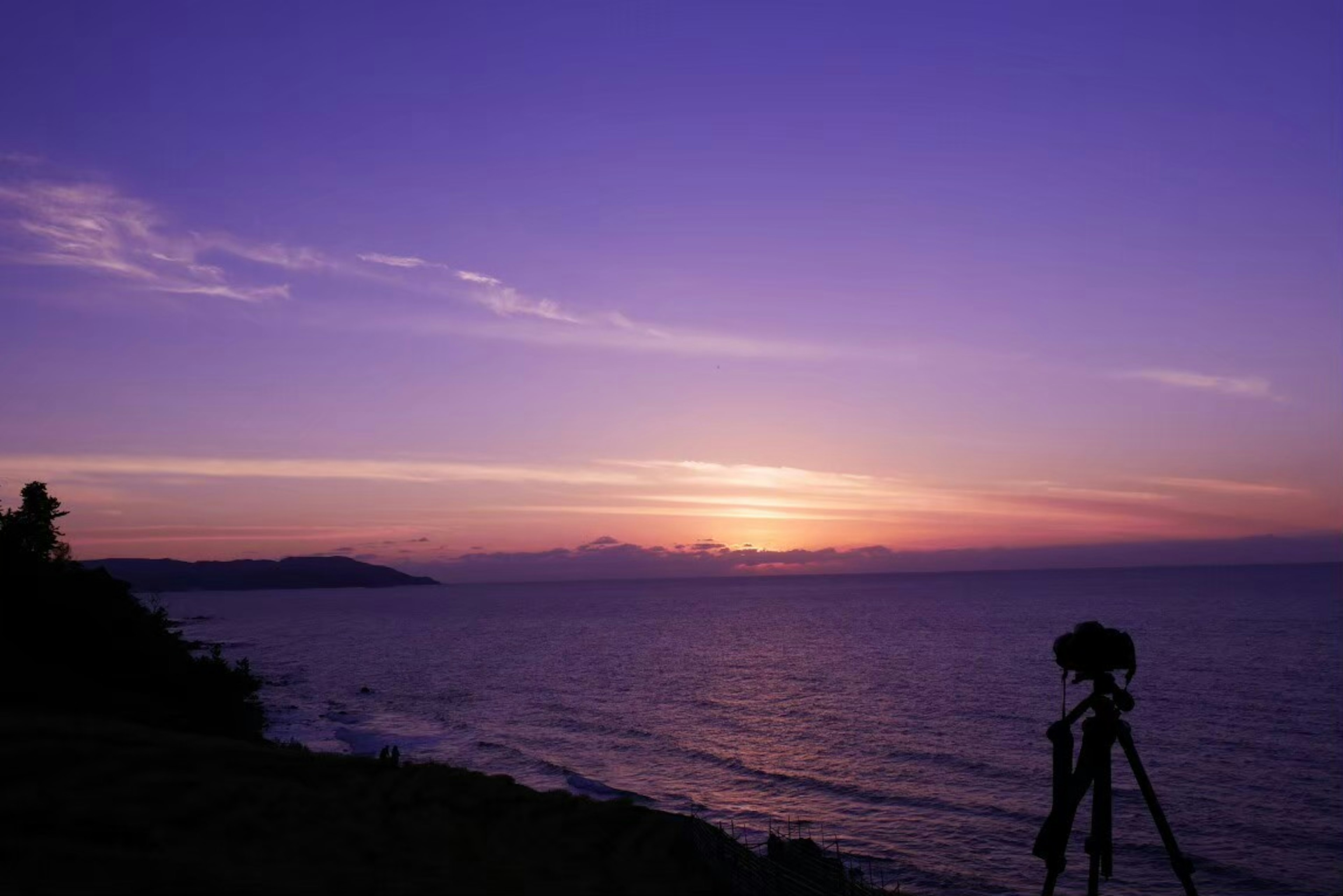 Pemandangan laut dan langit ungu dengan tripod