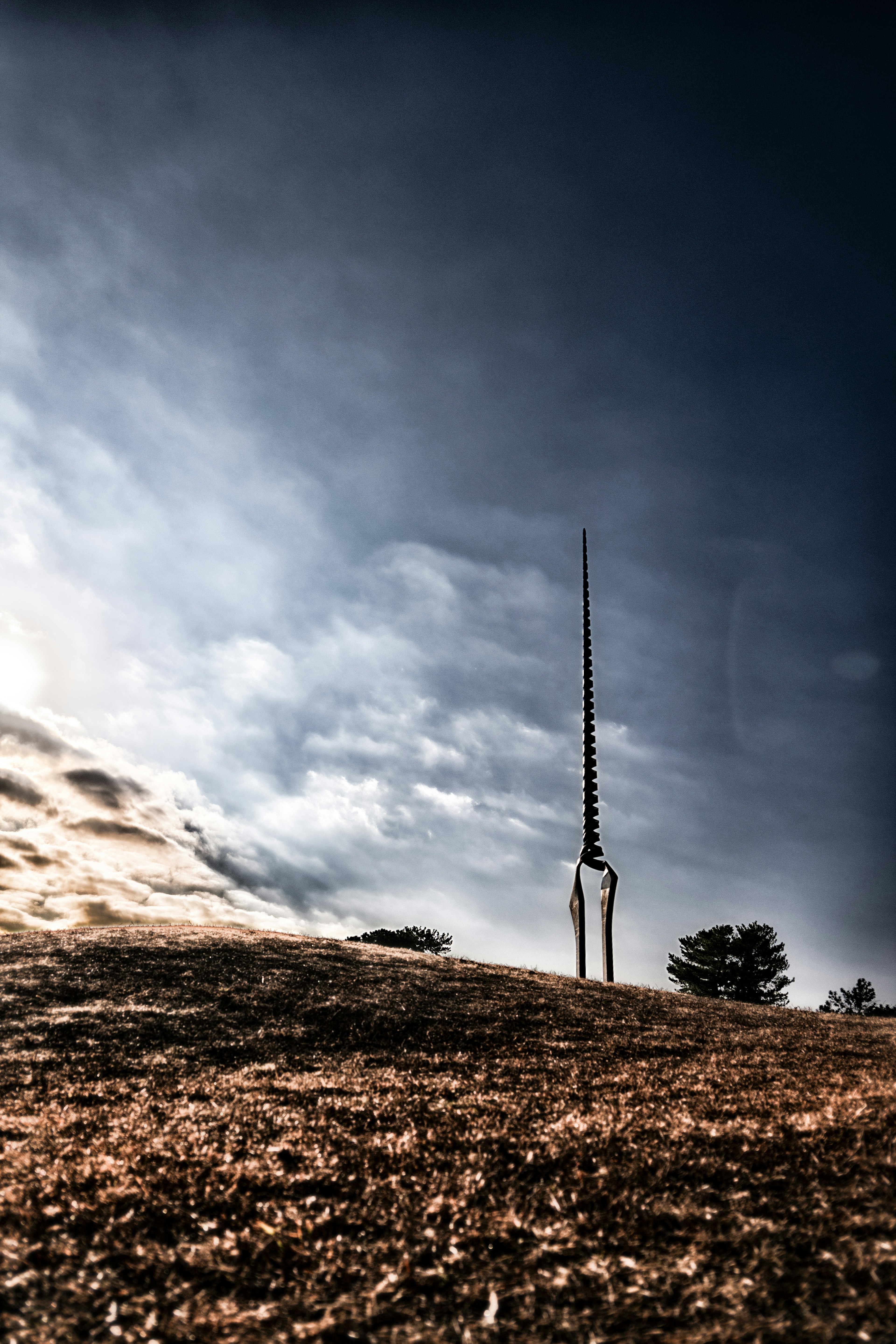 Alta torre de comunicación en una colina con un cielo dramático