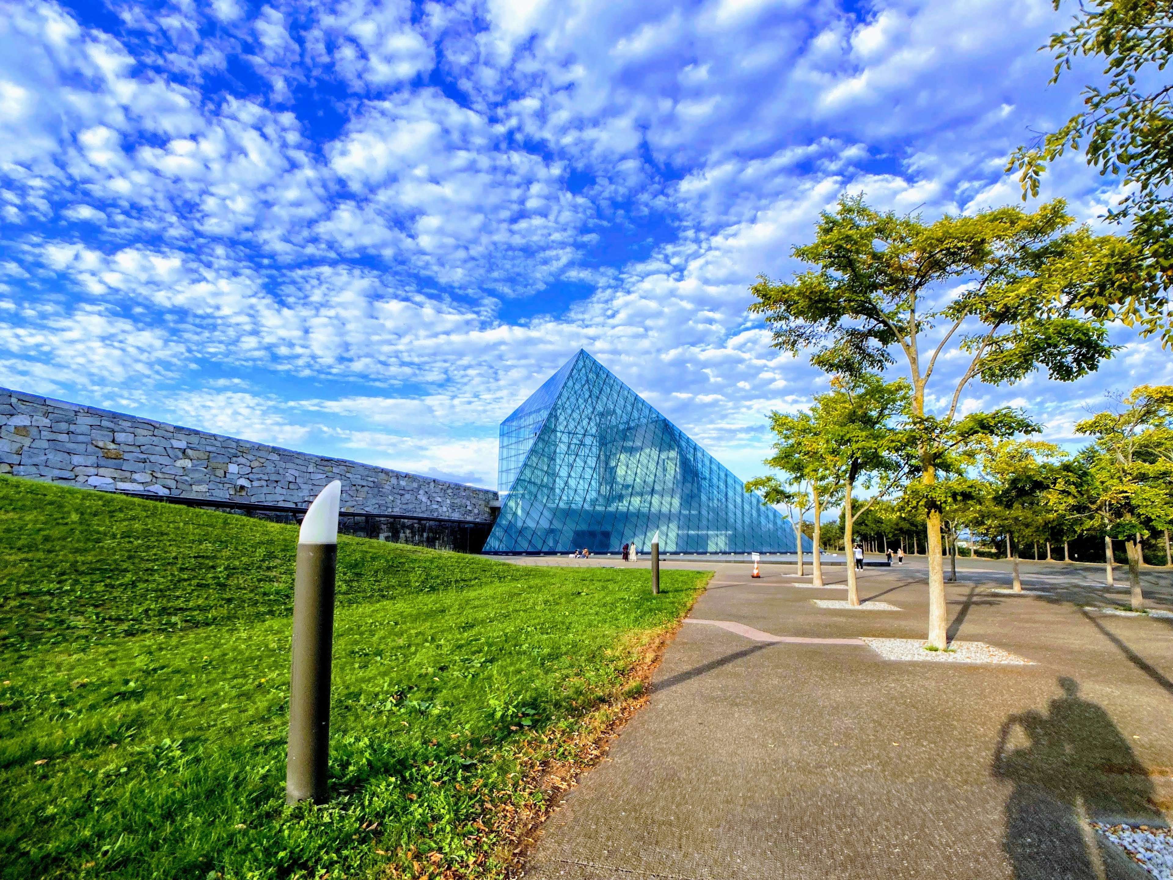 Modern glass building set against a blue sky with white clouds and green grass