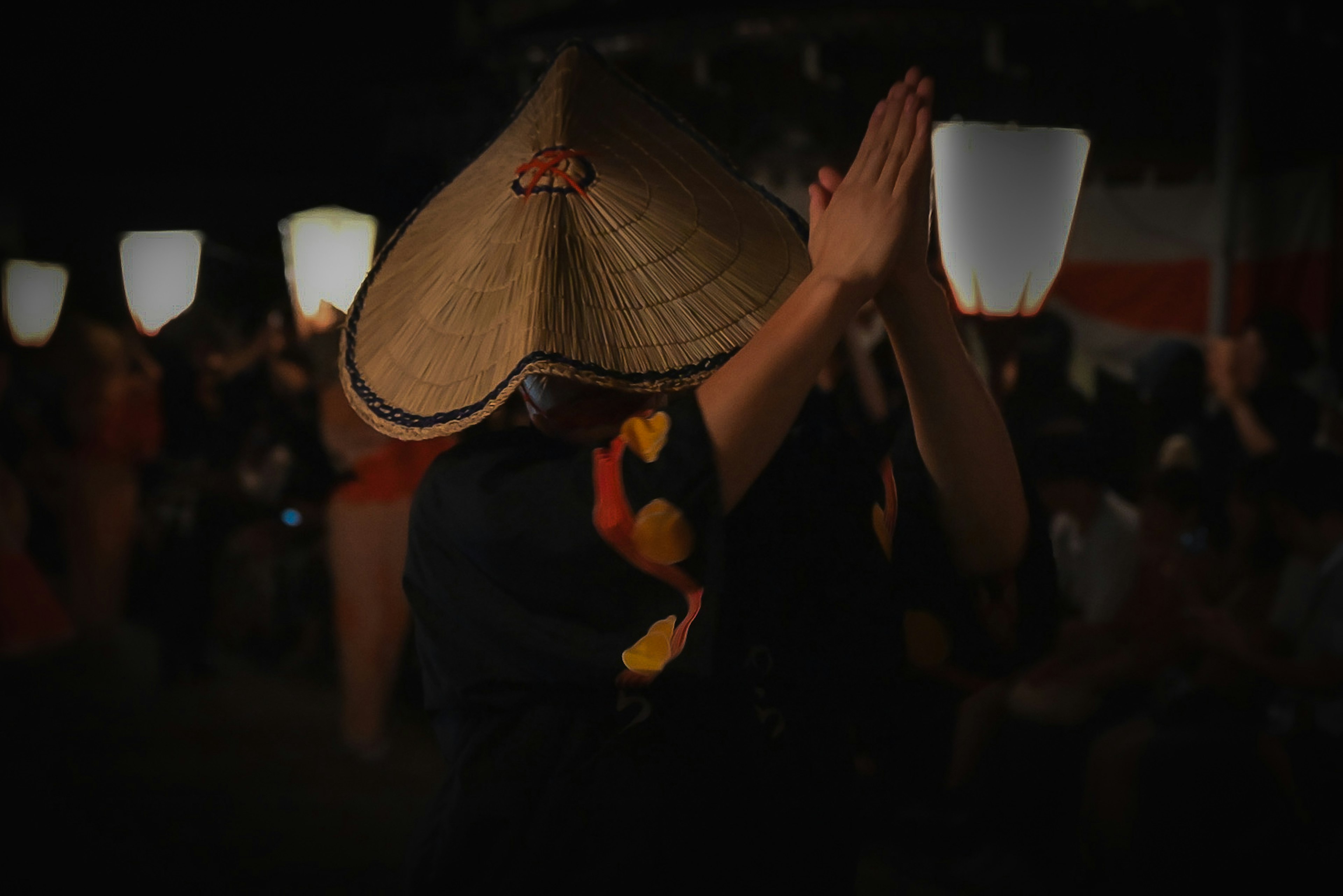 Orang menari di festival malam mengenakan topi tradisional