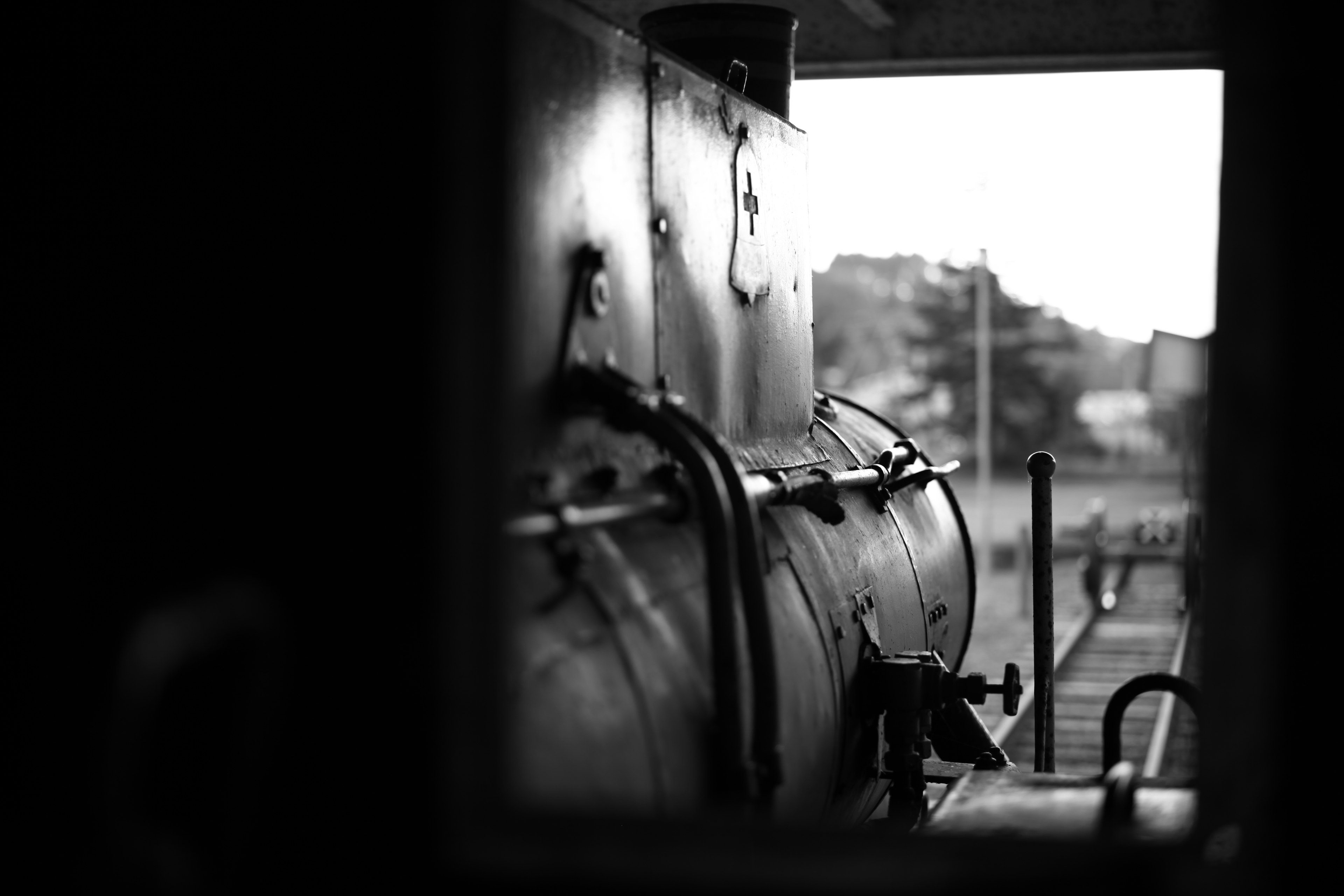 Vista en blanco y negro del lado de una locomotora de vapor a través de una ventana