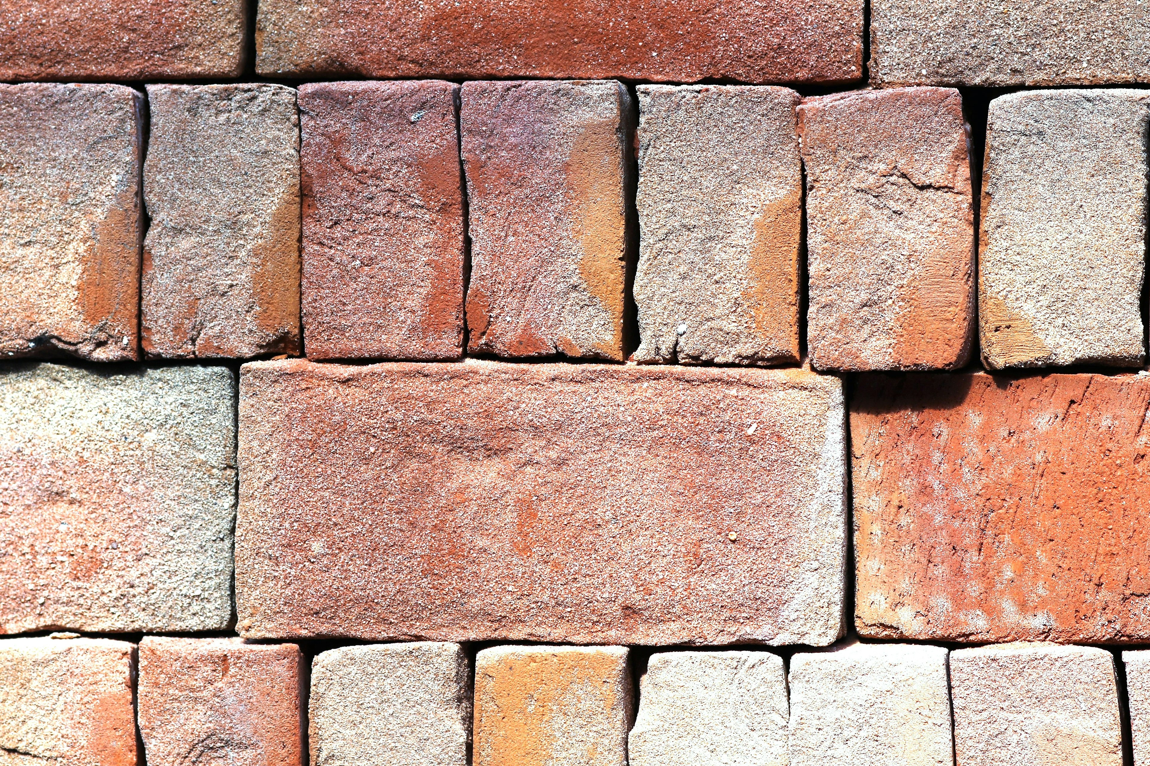 A textured wall of red and gray bricks with varying colors and shapes