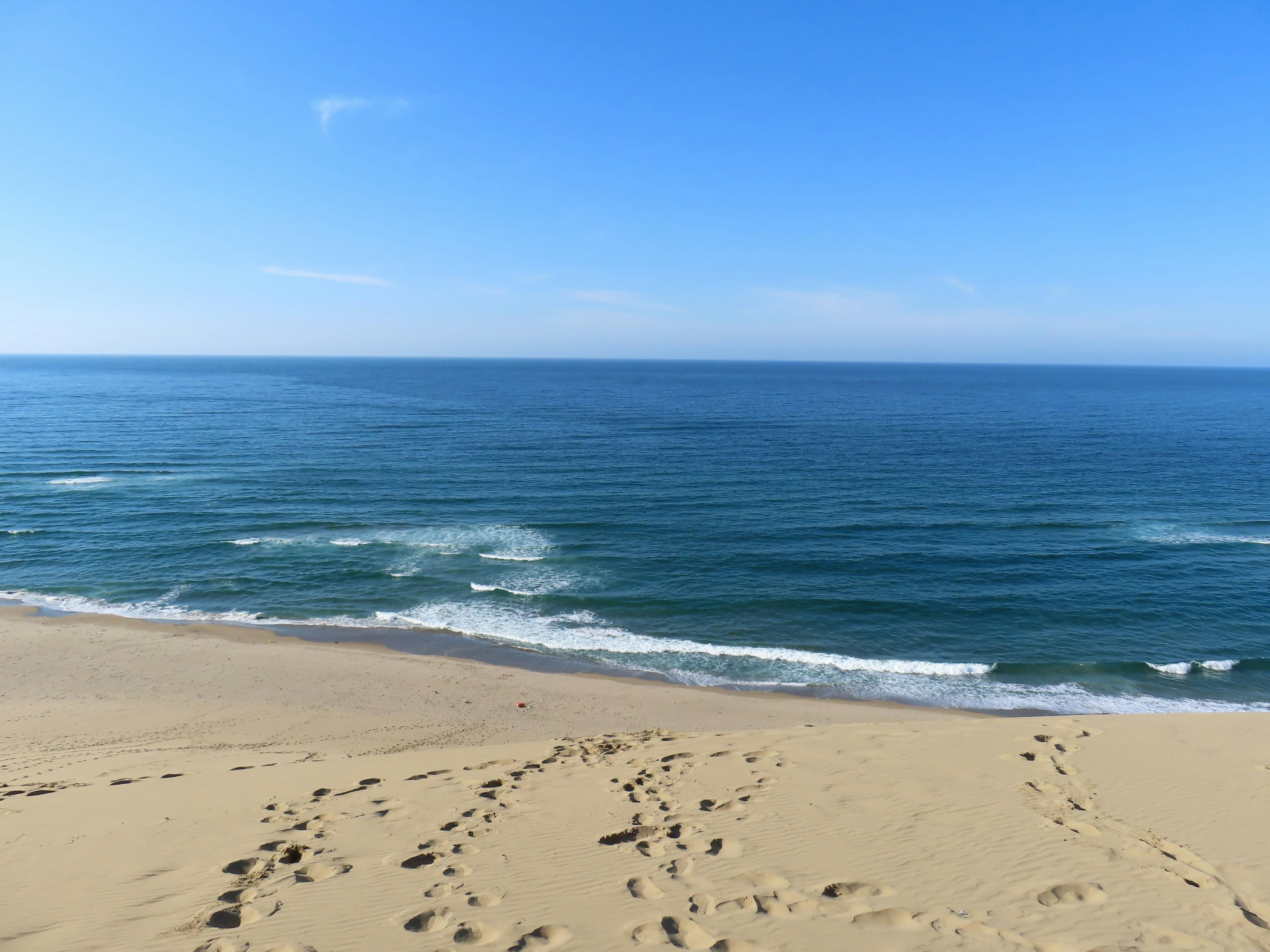 ทิวทัศน์ที่สวยงามของมหาสมุทรสีน้ำเงินและชายหาดทรายใต้ท้องฟ้าที่แจ่มใสพร้อมคลื่นอ่อน