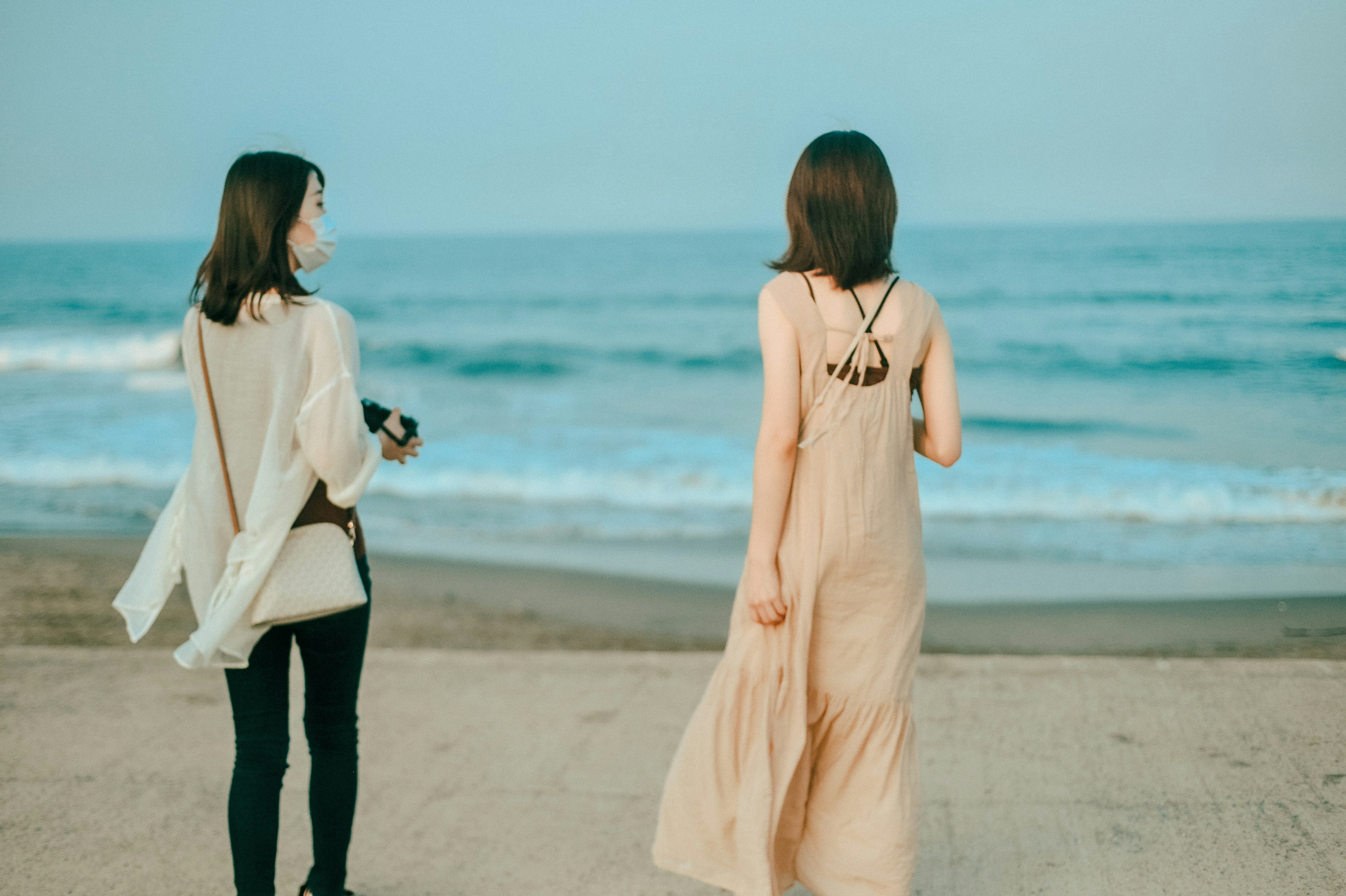 Zwei Frauen, die am Strand mit Ozeanwellen spazieren