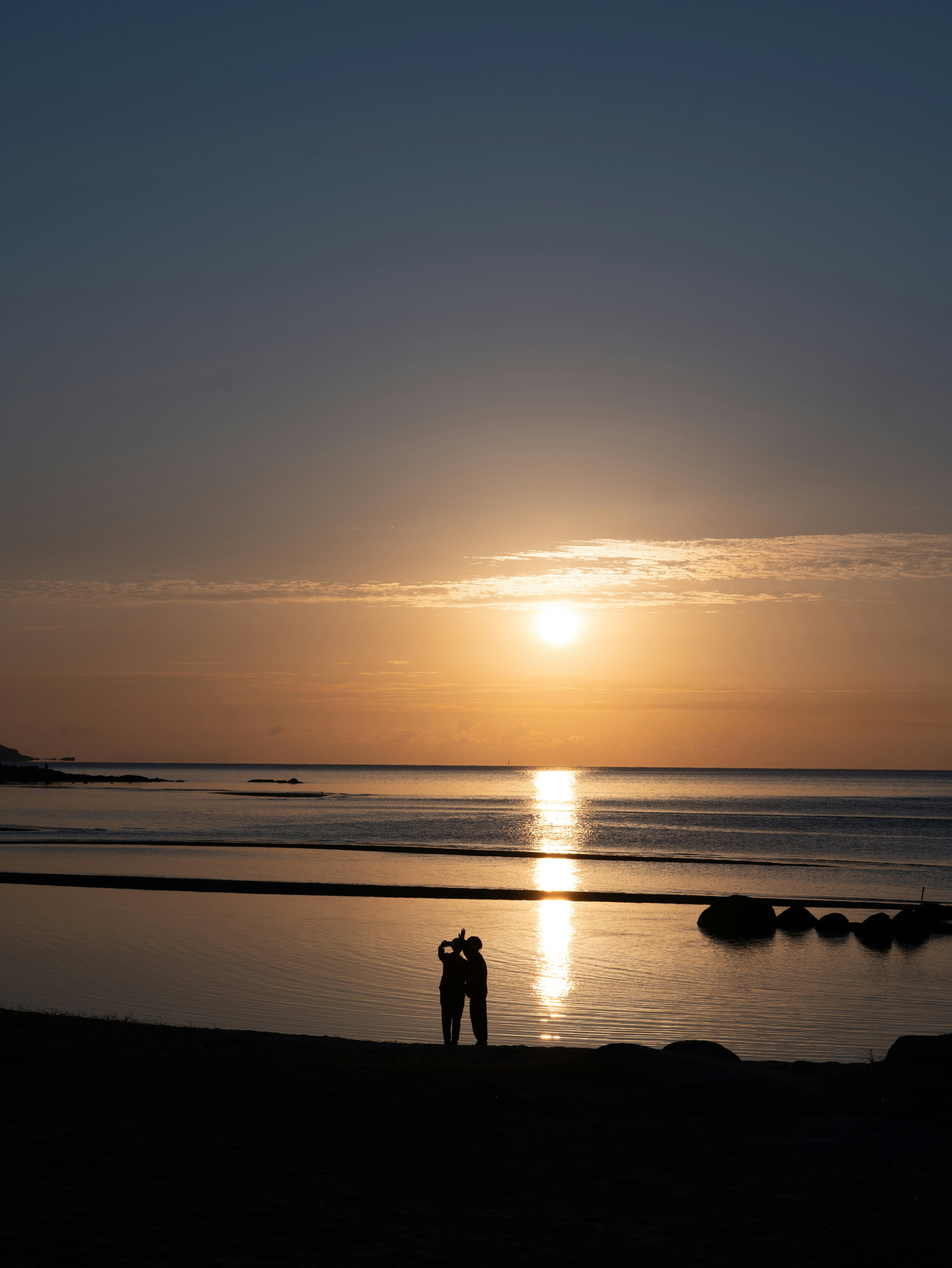 Silhouette d'un couple au coucher du soleil sur la plage créant une scène romantique