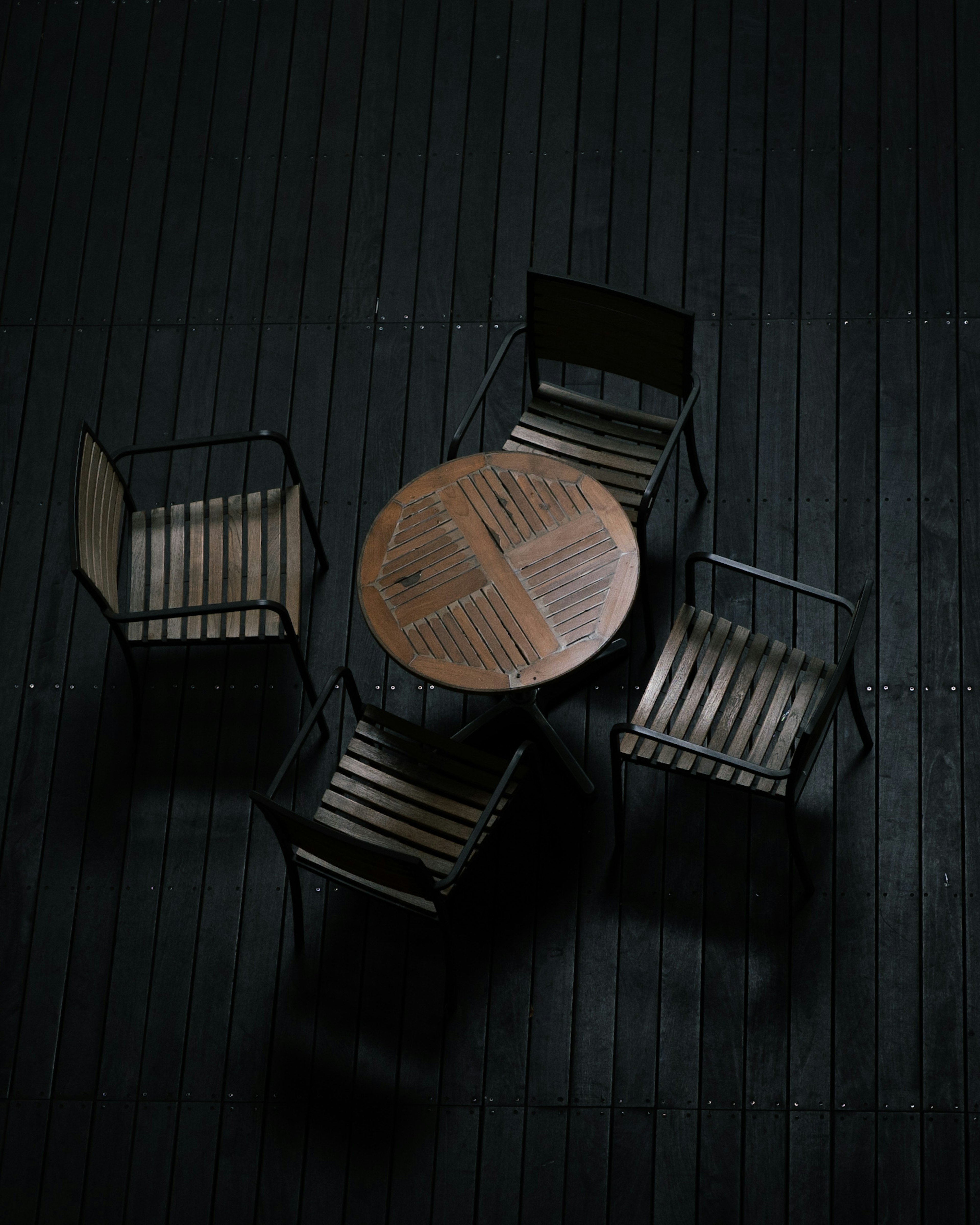 Wooden table and metal chairs arranged on a dark floor