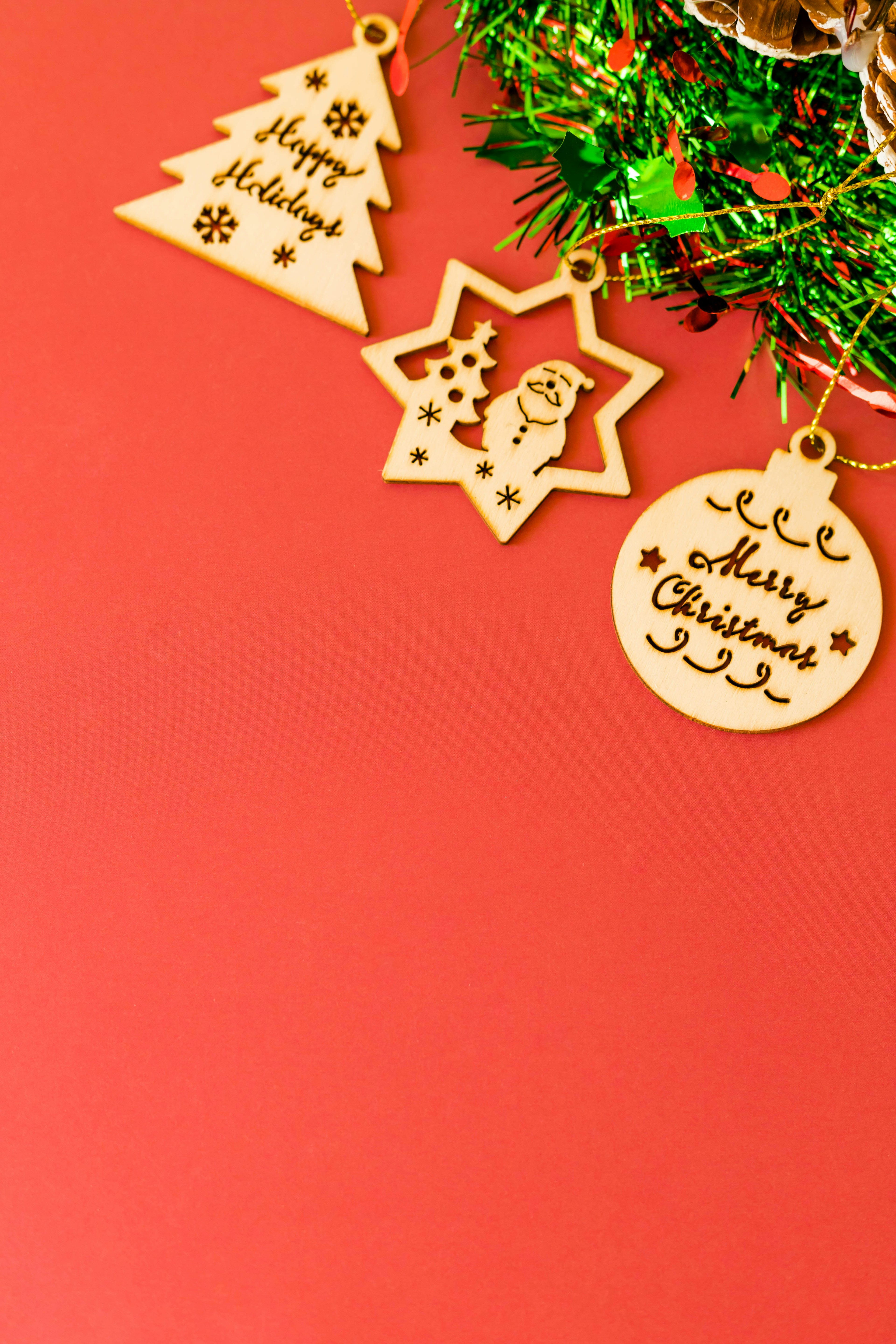 Holz-Weihnachtsornamente auf rotem Hintergrund mit einem Baum, einem Stern und runden Designs mit festlichen Botschaften