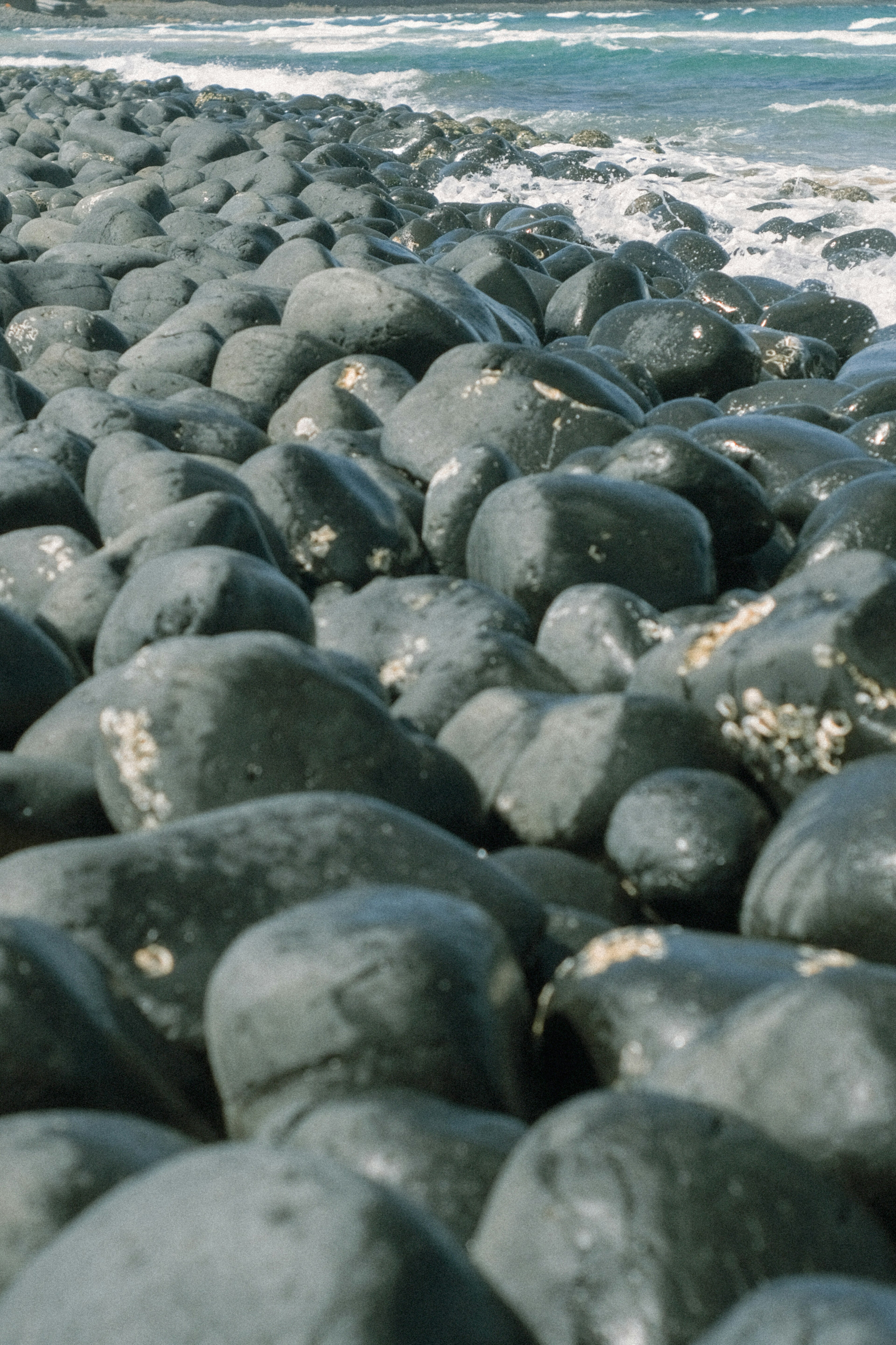 Küstenansicht von schwarzen Steinen, die von Wellen gewaschen werden