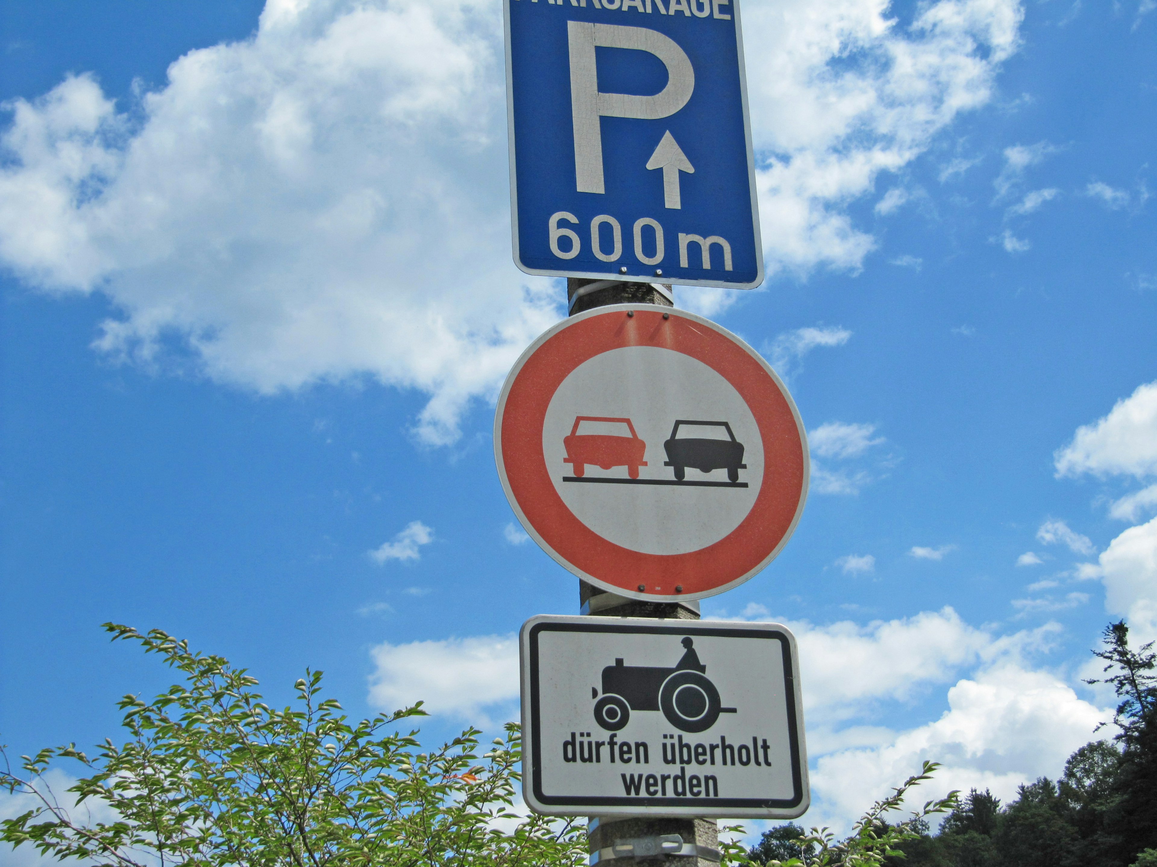 Cartello di parcheggio che indica 600 metri fino all'area di sosta con un segnale blu e un segnale rosso di divieto per i veicoli