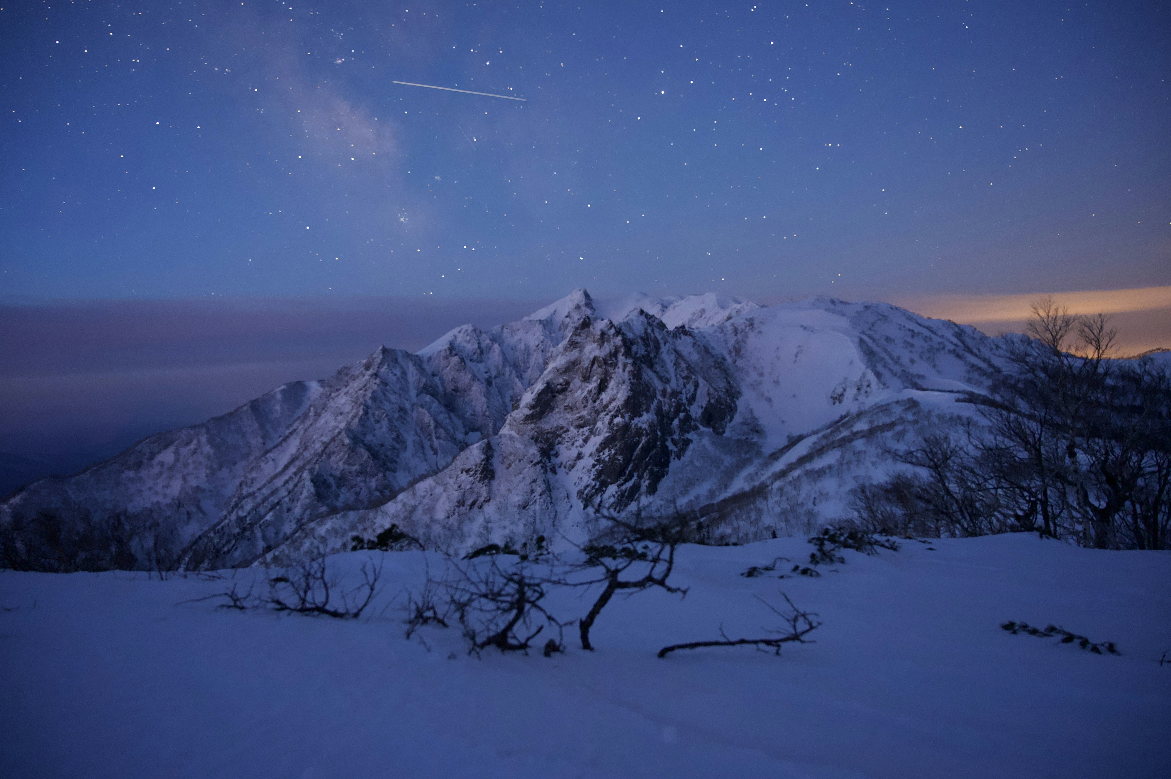 Snow-covered mountains under a night sky filled with stars