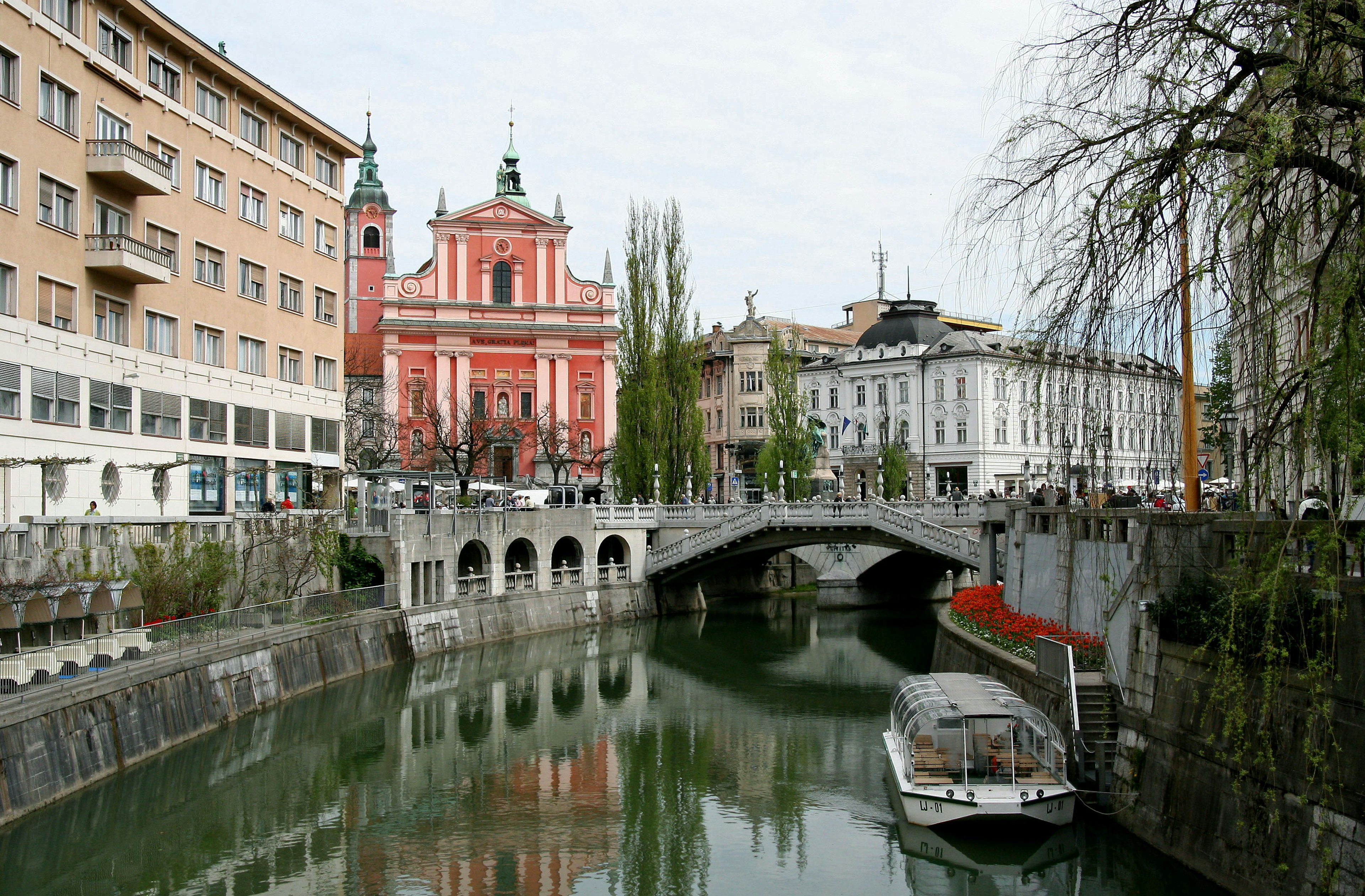 Cảnh sông Ljubljanica với cây cầu và nhà thờ hồng ở phía sau