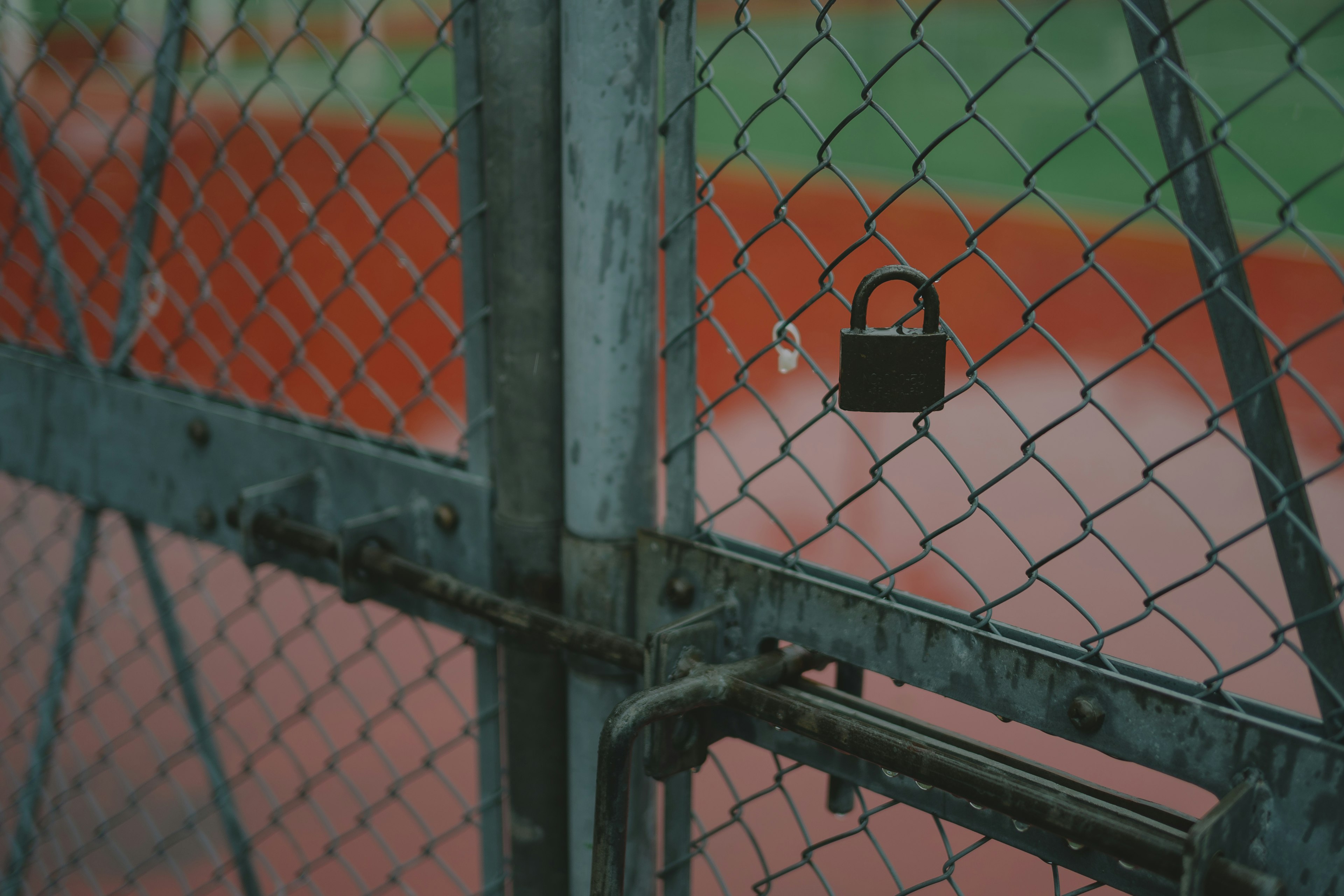 Imagen de una puerta cerrada con una cerca de metal y un candado negro