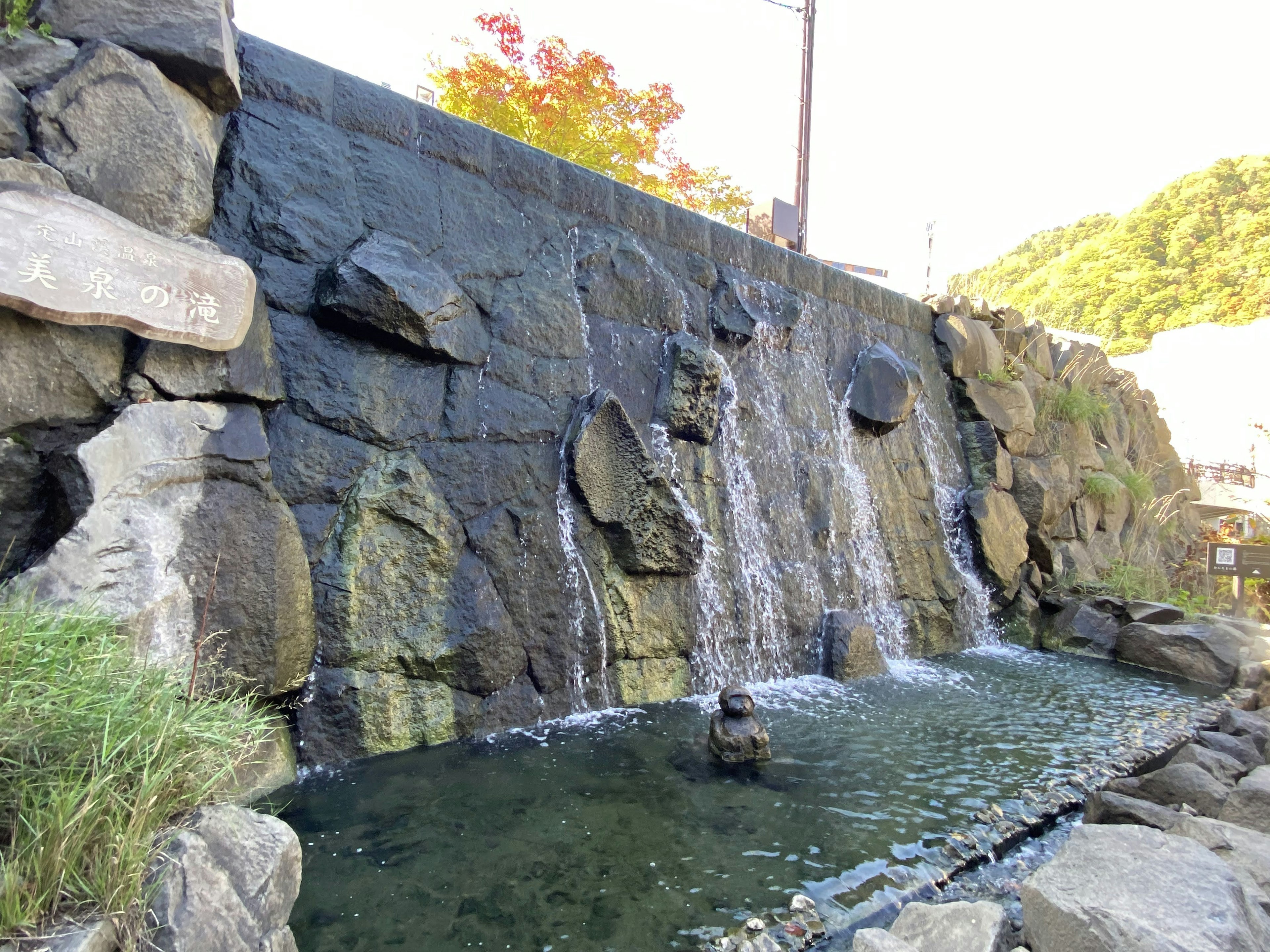 Waterfall cascading over a stone wall into a serene pond