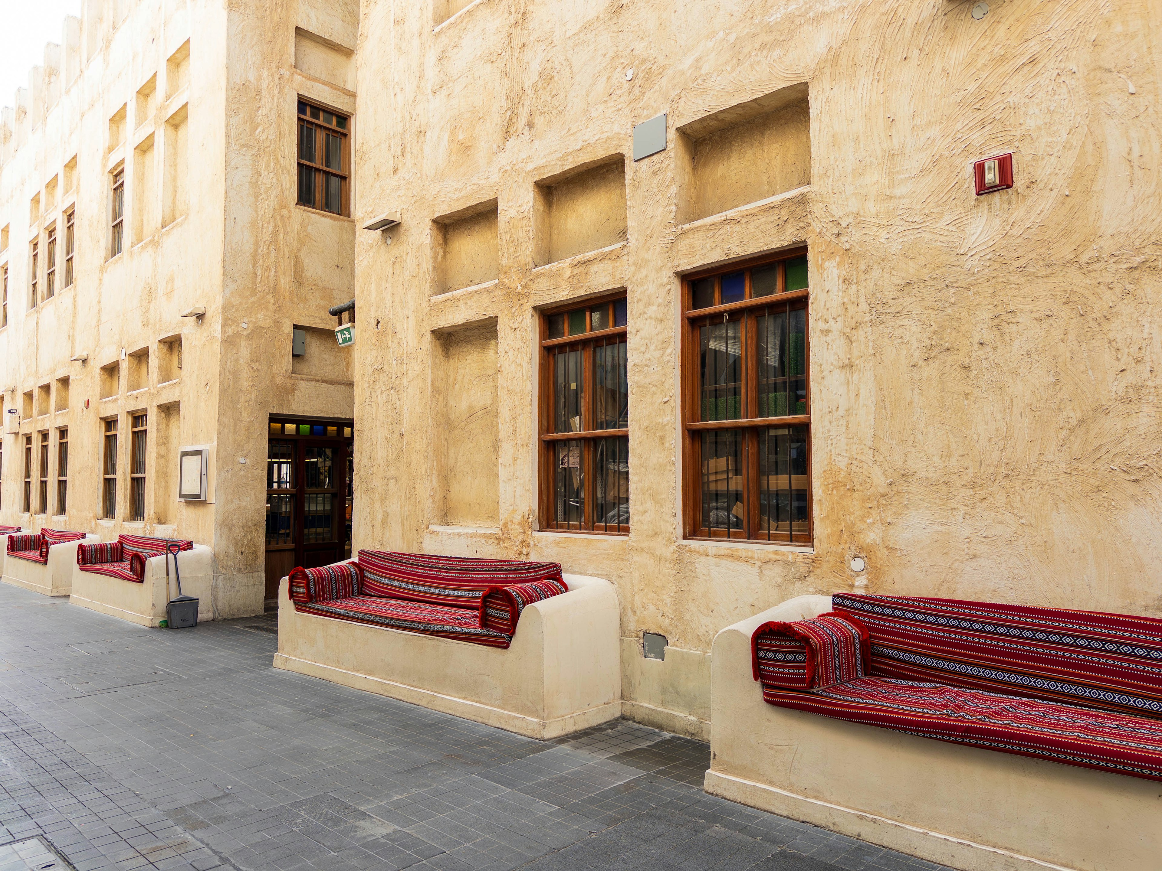 Extérieur d'un bâtiment avec des murs clairs et des bancs rouges