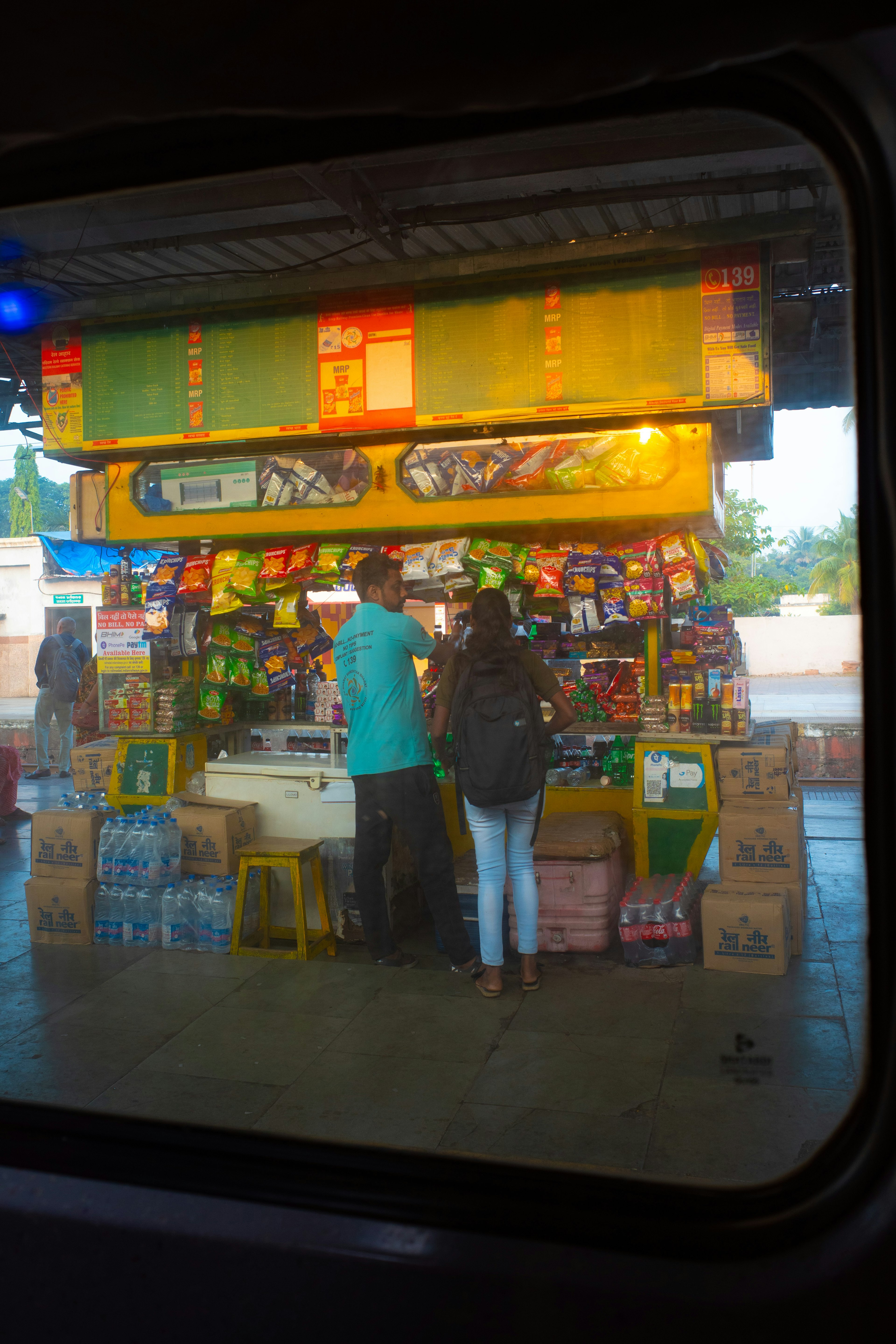 Dua orang memilih barang di kios stasiun Berbagai minuman dan camilan ditampilkan