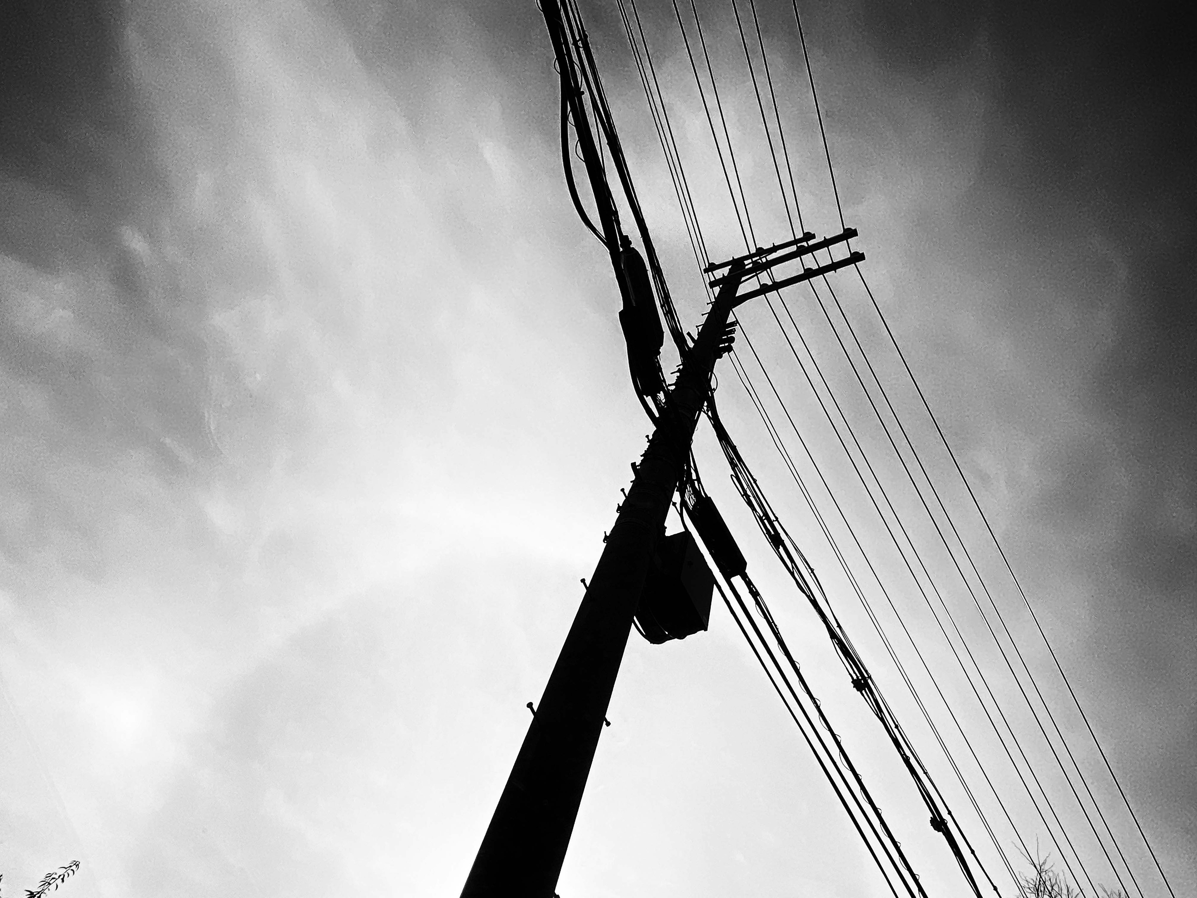 Photo en noir et blanc d'un grand poteau électrique avec des lignes électriques